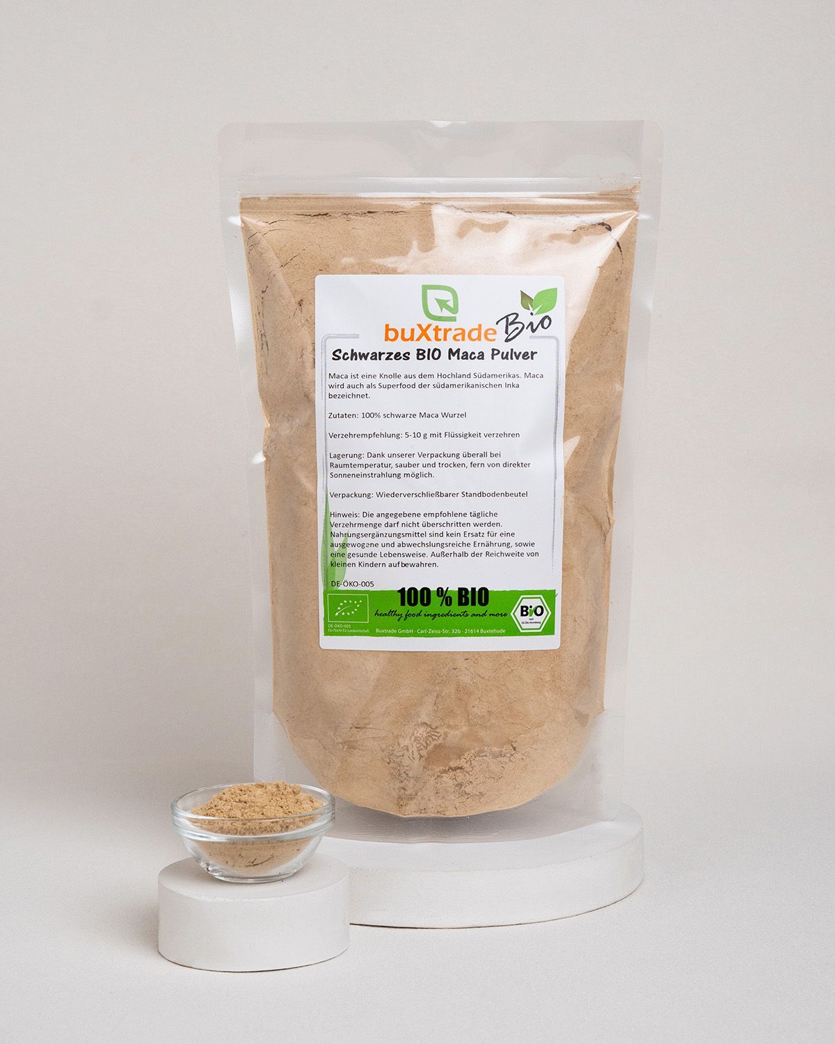 Transparente Verpackung mit braunem Pulver, daneben eine kleine Glasschale mit Pulver. Bio-Siegel.