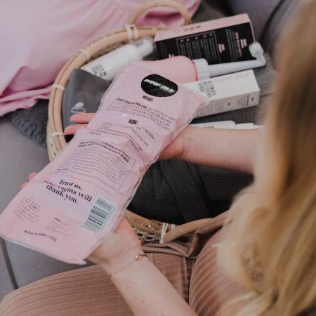 Rosa Kühlbinde in Folienverpackung. Text: "Instant Cooling Vag Pads". Weitere Produkte im Korb.