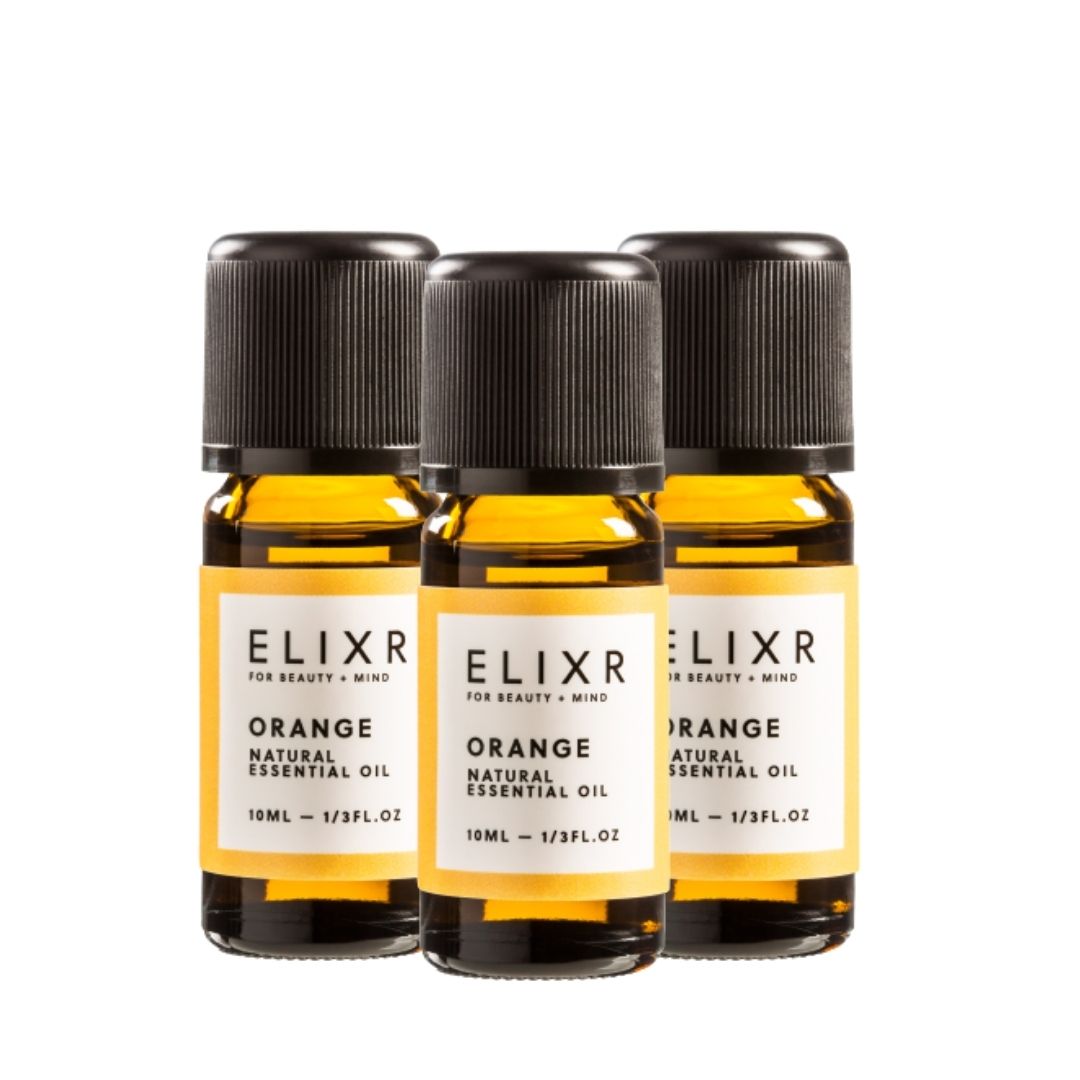 Drei Flaschen ELIXR Orangenöl. Braune Glasflaschen mit schwarzem Deckel und Etikett. Aufschrift: Orange Natural Essential Oil.