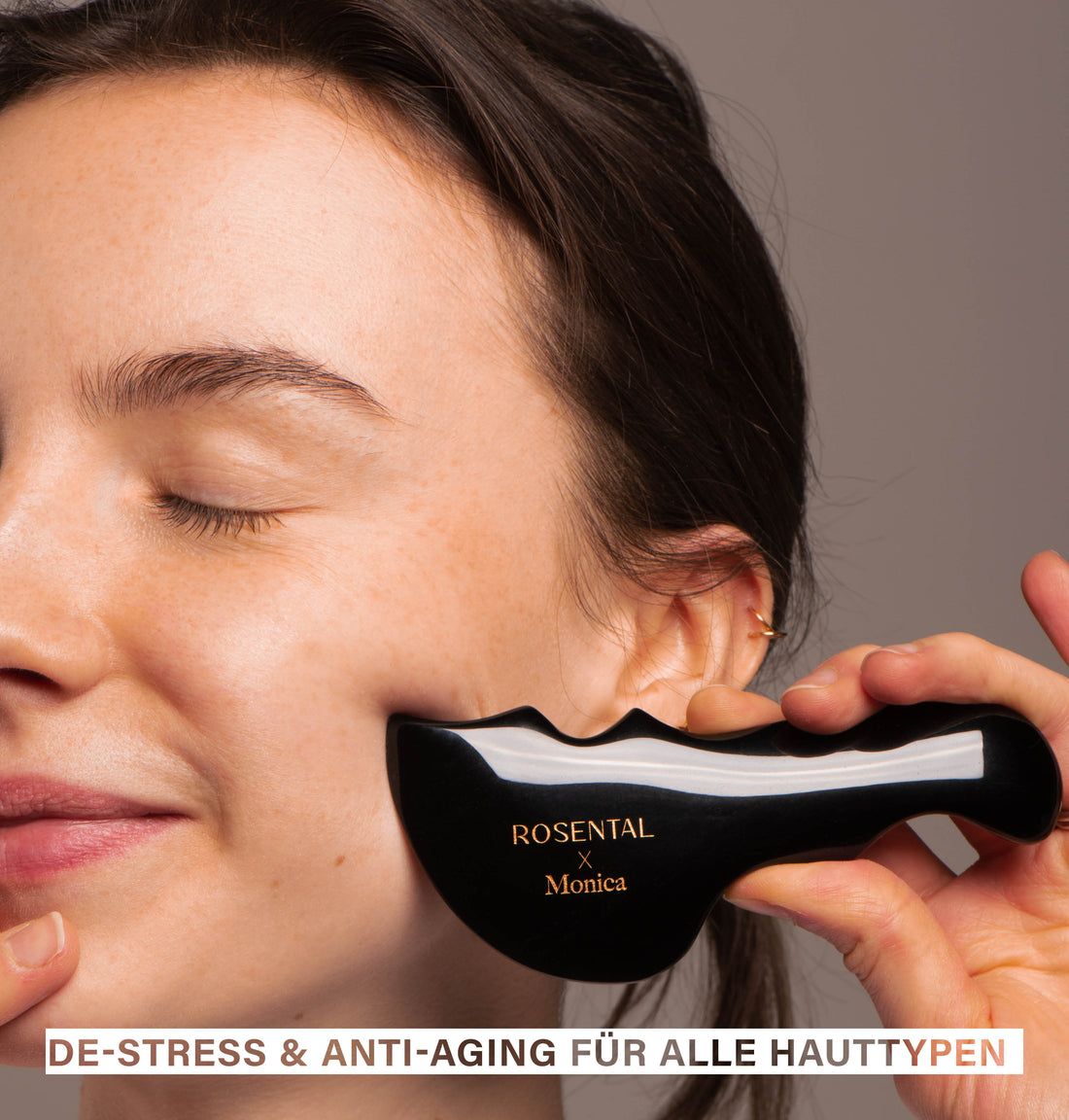Frau mit Gua Sha an der Wange. Schwarzes Obsidian-Tool. Goldfarbener Schriftzug: ROSENTAL x Monica. Text: DE-STRESS & ANTI-AGING FÜR ALLE HAUTTYPEN.