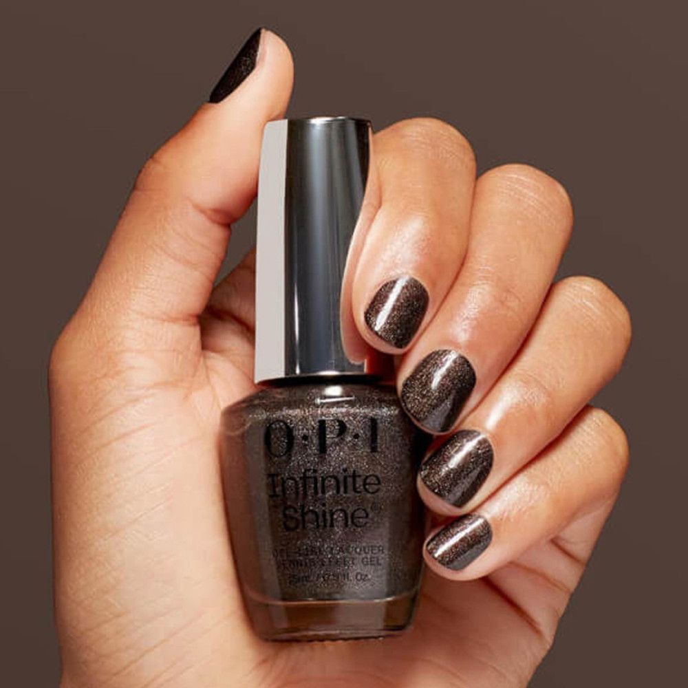 Hand mit lackierten Nägeln und Nagellackflasche. OPI Infinite Shine, dunkelbraune Farbe. Silberner Deckel.