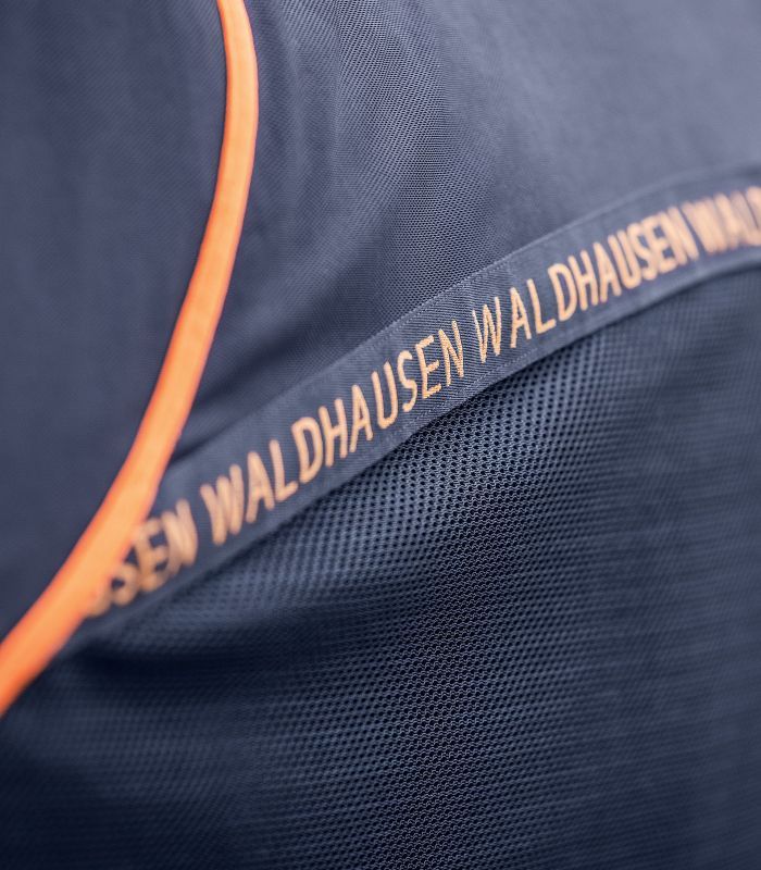 Nahaufnahme der blauen Pferdedecke mit orangefarbenem Rand. Aufschrift: WALDHAUSEN. Mesh-Gewebe sichtbar.