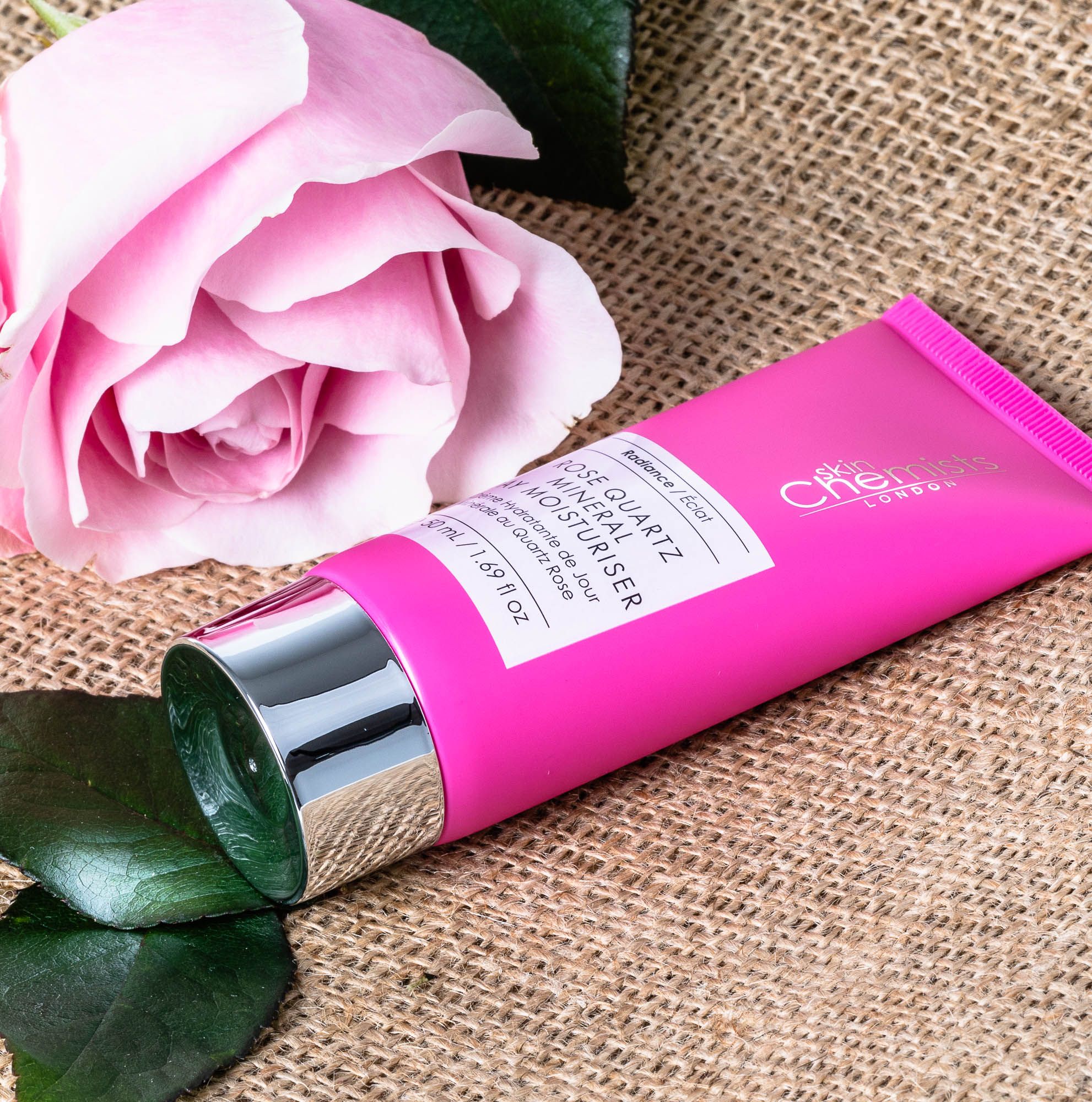 Rosa Tube mit Produktname, neben Rose. Text: Rose Quartz Mineral Day Moisturiser. Marke: skinChemists.