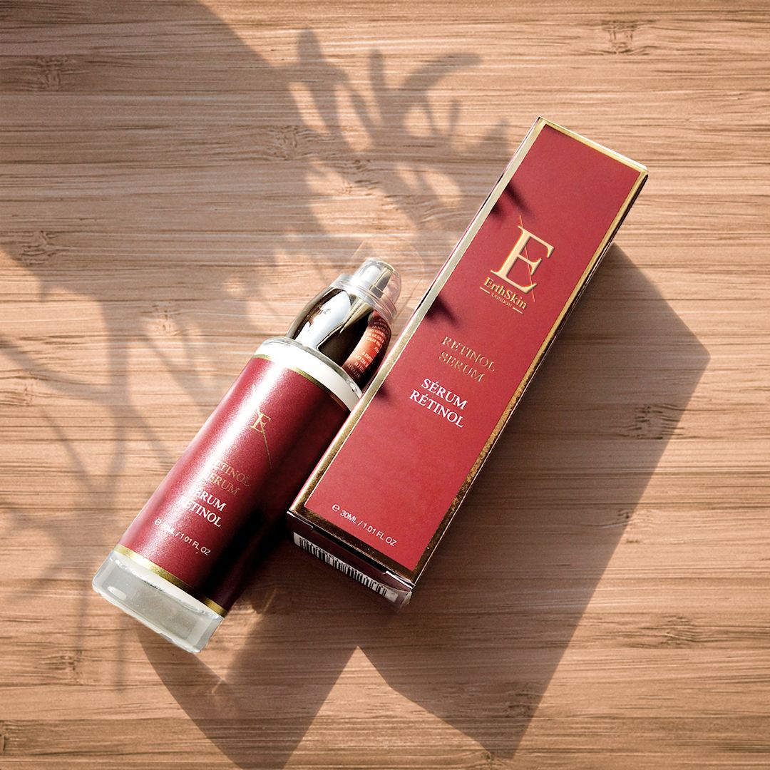 Retinol-Serum-Flasche und -Verpackung auf Holzoberfläche. Flasche und Verpackung in Rot und Gold. Schattenwurf.