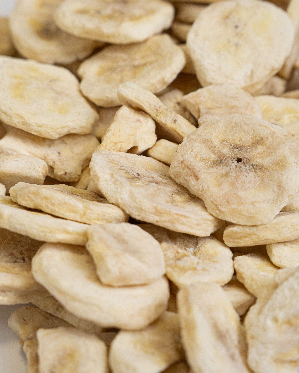 Nahaufnahme von gefriergetrockneten Bananenscheiben. Die Scheiben sind hellbraun und zeigen die Struktur.