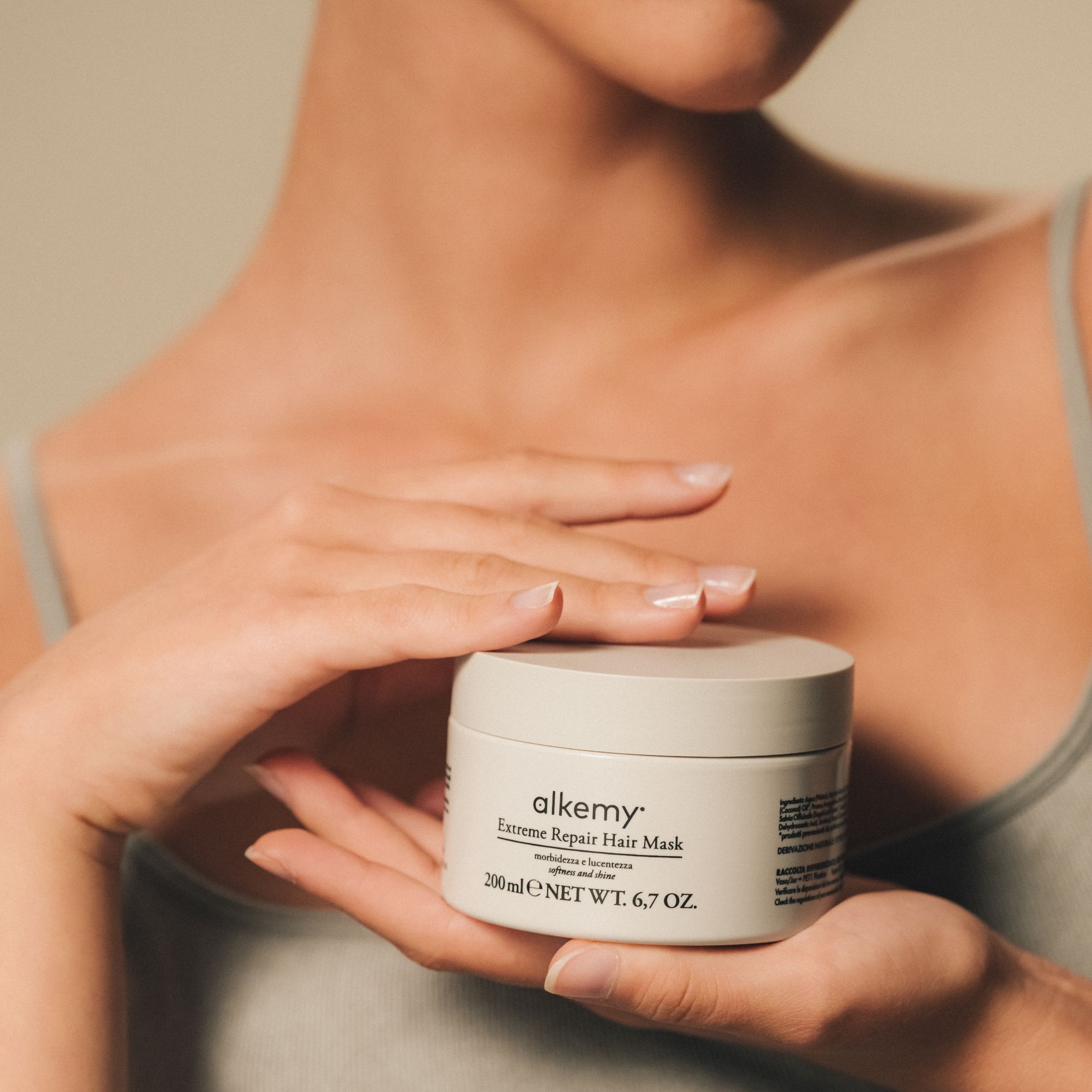 Frau hält einen Tiegel mit Alkemy Intense Repair Haarmaske.