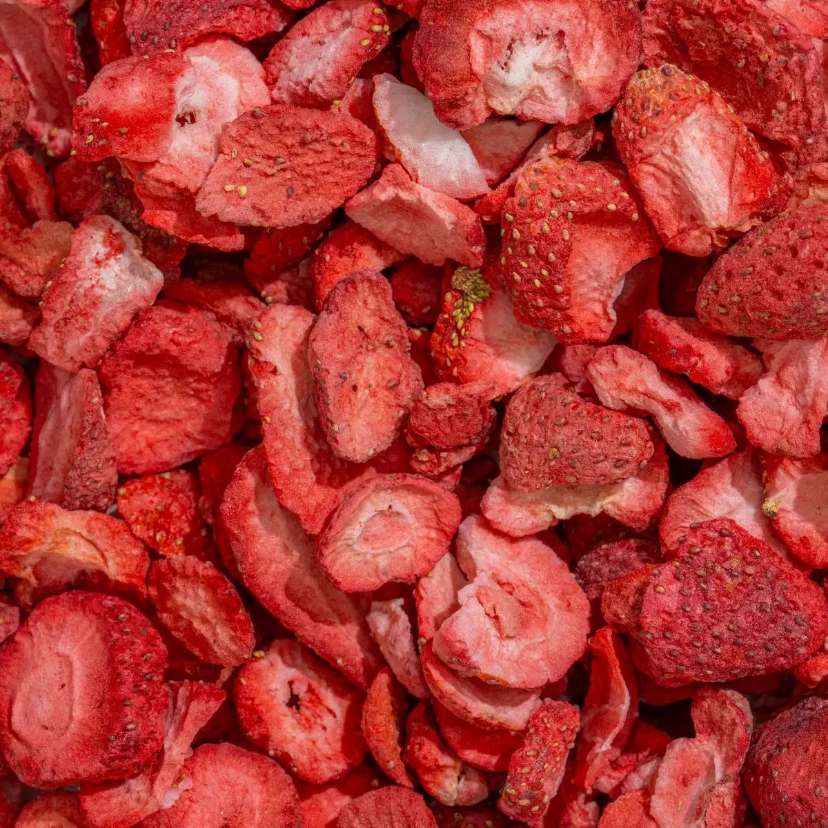 Nahaufnahme von gefriergetrockneten Erdbeerstücken. Rote Farbe, unterschiedliche Formen und Größen. Einige Stücke sind sichtbar.