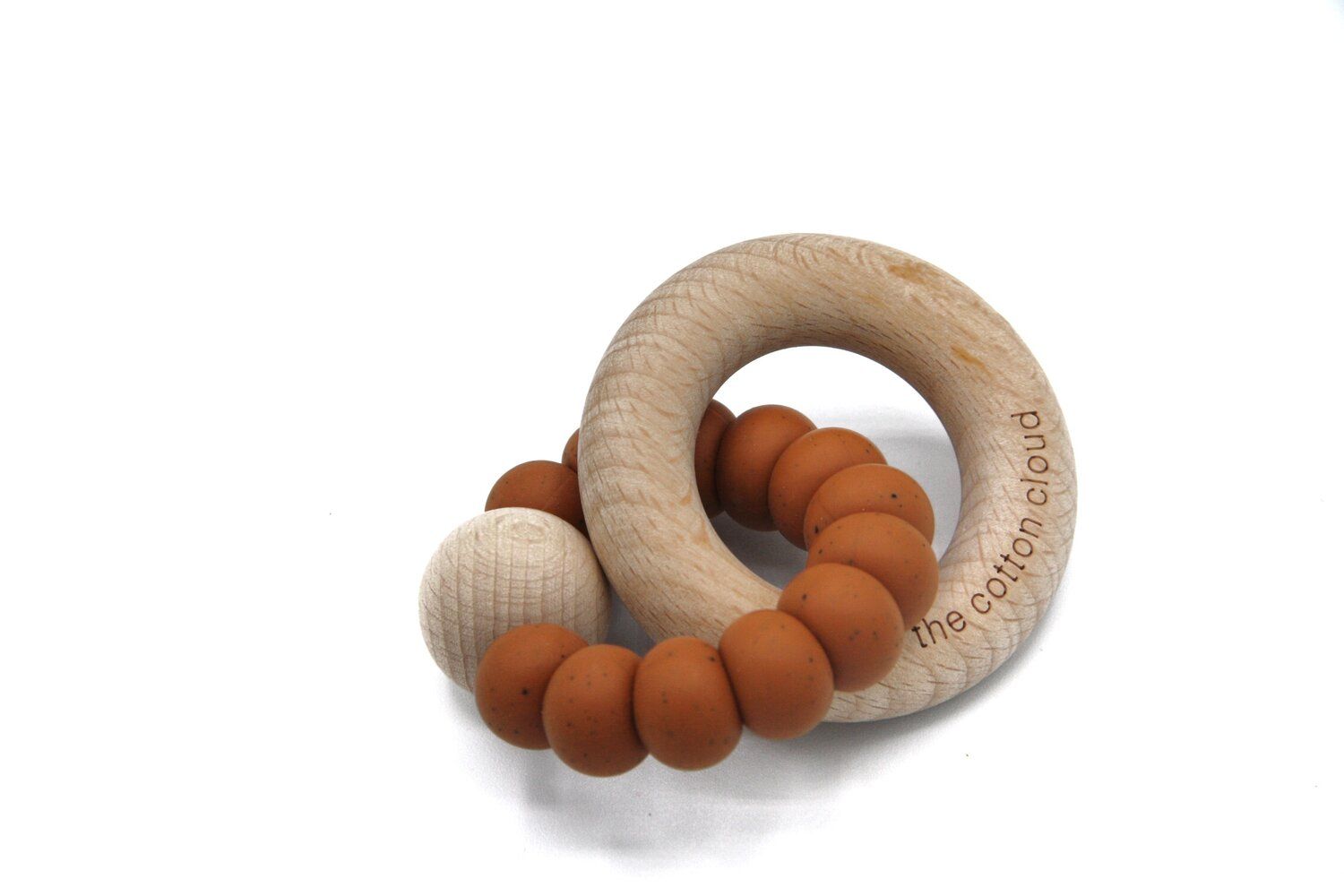Beißring aus Holz und Silikon. Ringförmiger Holzring mit Silikonperlen und einer Holzkugel. Aufschrift: the cotton cloud.