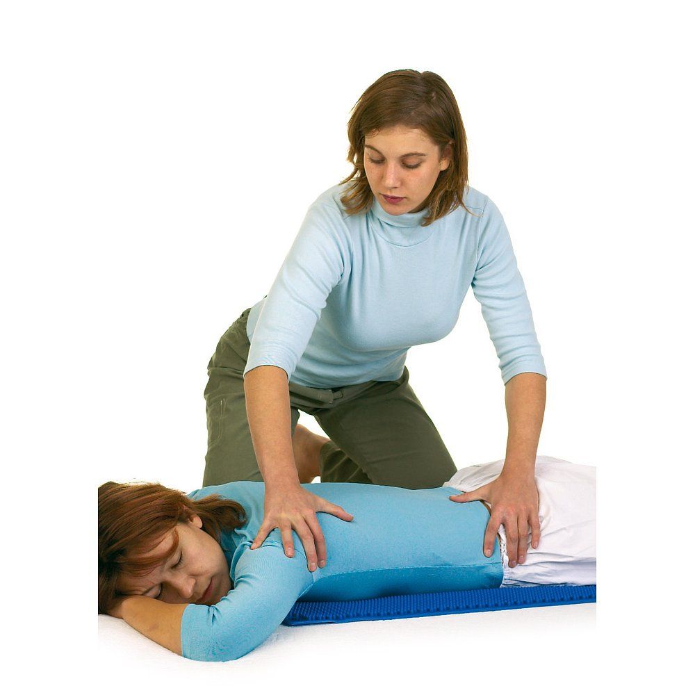 Blaue Massagematte. Frau liegt, eine andere Frau massiert ihren Rücken.