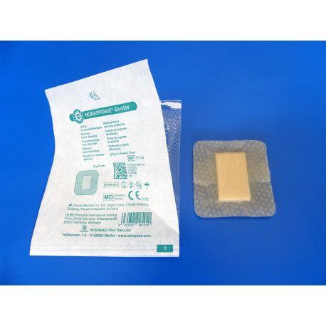 Verpackung mit einem Verband. Der Verband ist quadratisch mit einem hellen, rechteckigen Kern und einer transparenten Umrandung. Verpackung mit Text.