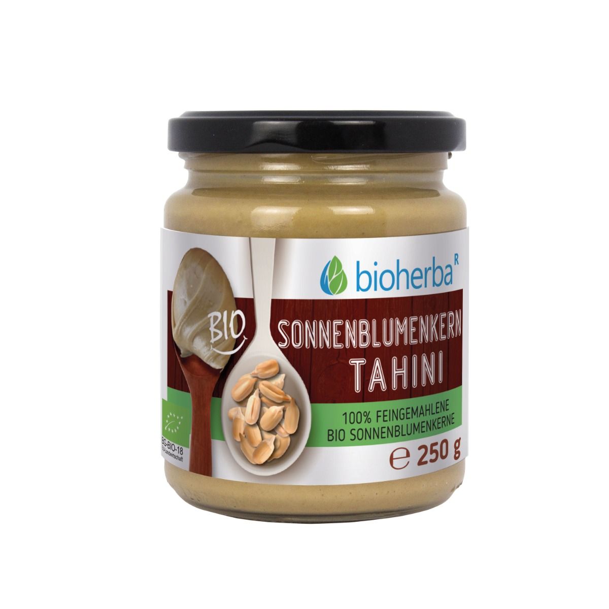 Glas mit schwarzem Deckel. Etikett mit "Bioherba Sonnenblumenkern Tahini". Löffel mit Tahini und Sonnenblumenkernen.