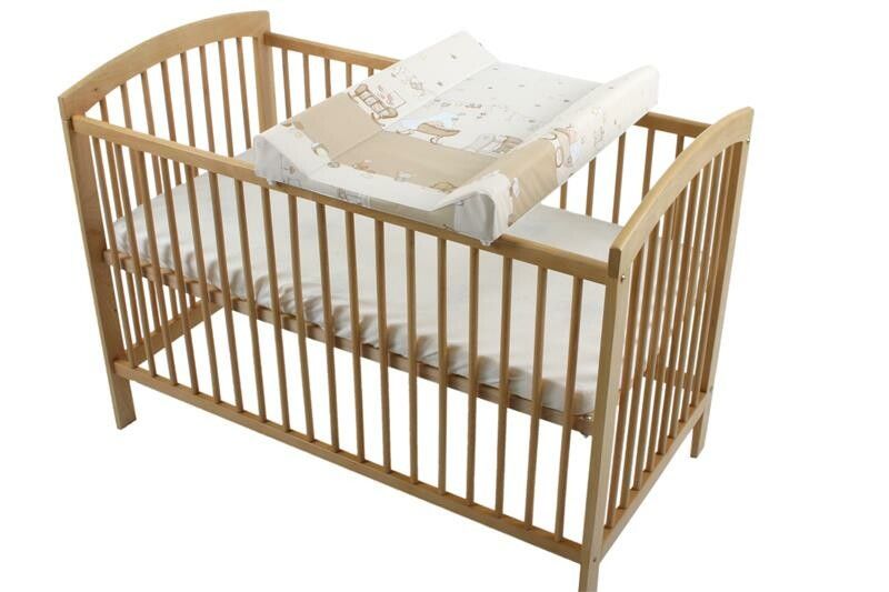 Holzbett mit Wickelauflage. Die Auflage liegt auf dem Bett und hat ein Muster.