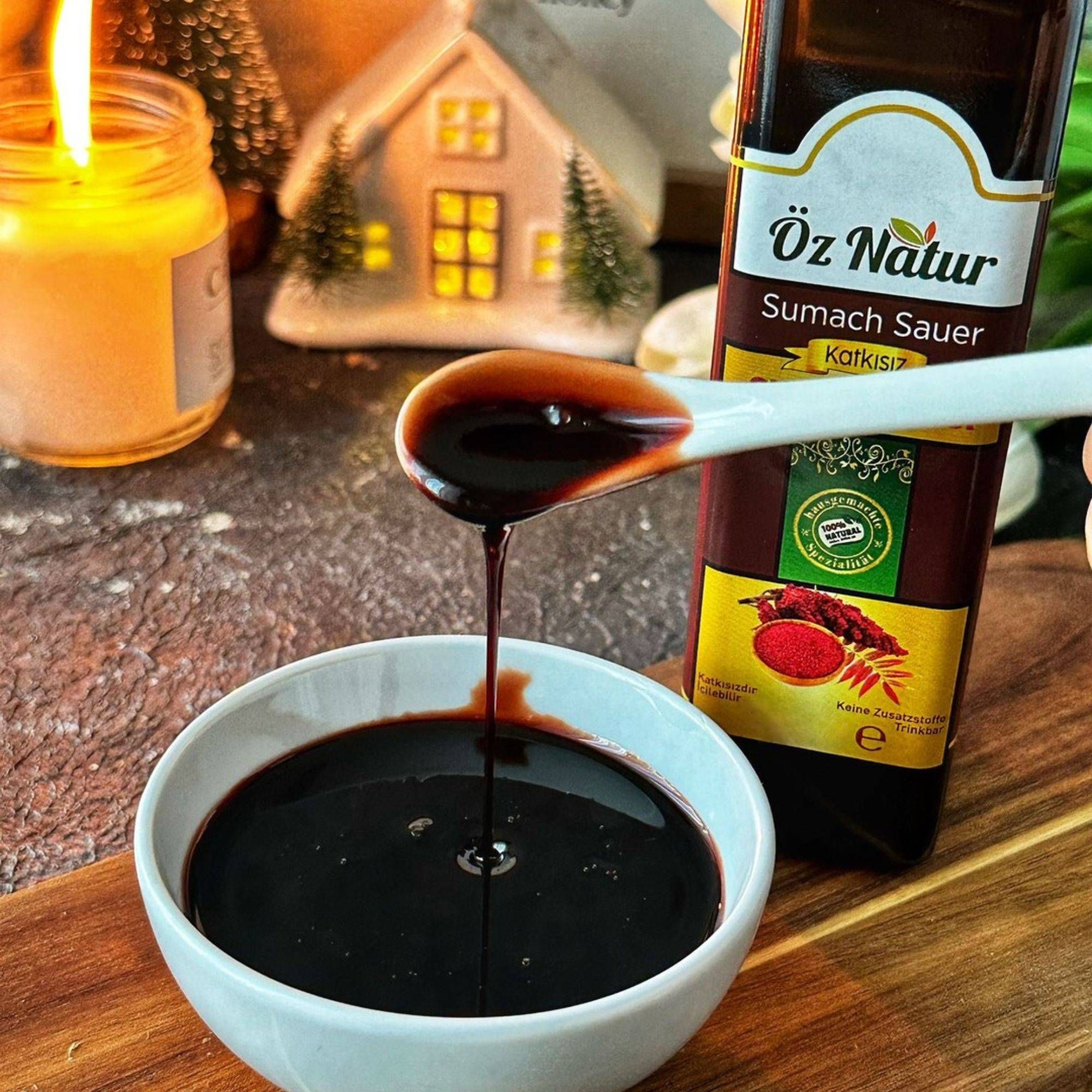 Flasche Öz Natur Sumach Sauer mit Löffel und Schale voller dunkler Sauce.