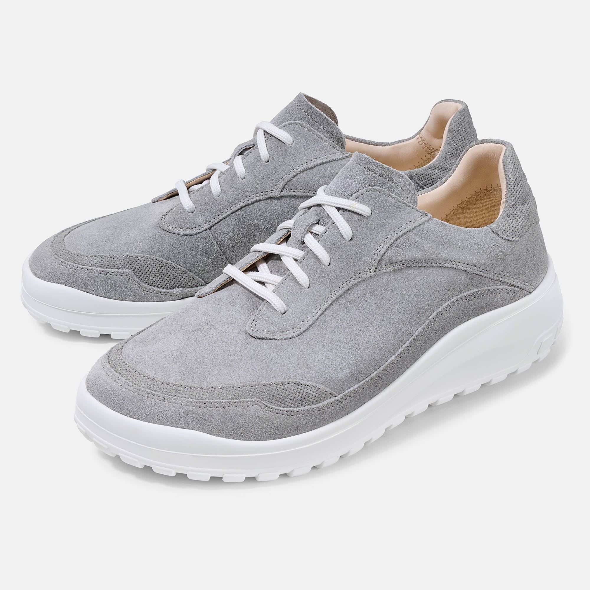 Graue Schnürschuhe mit weißer Sohle. Obermaterial aus Wildleder, weiße Schnürsenkel. Breite Form.