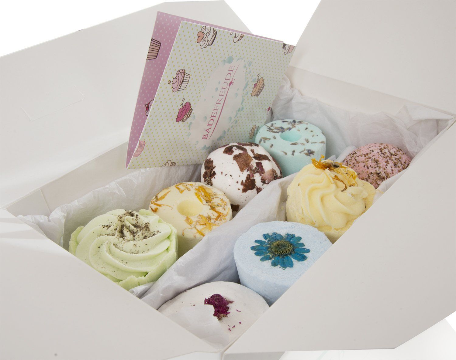 Geöffnete weiße Geschenkbox mit verschiedenen Badebomben und -kuchen. Einige sind rund, andere cupcake-förmig. Aufdruck "Badefreude".