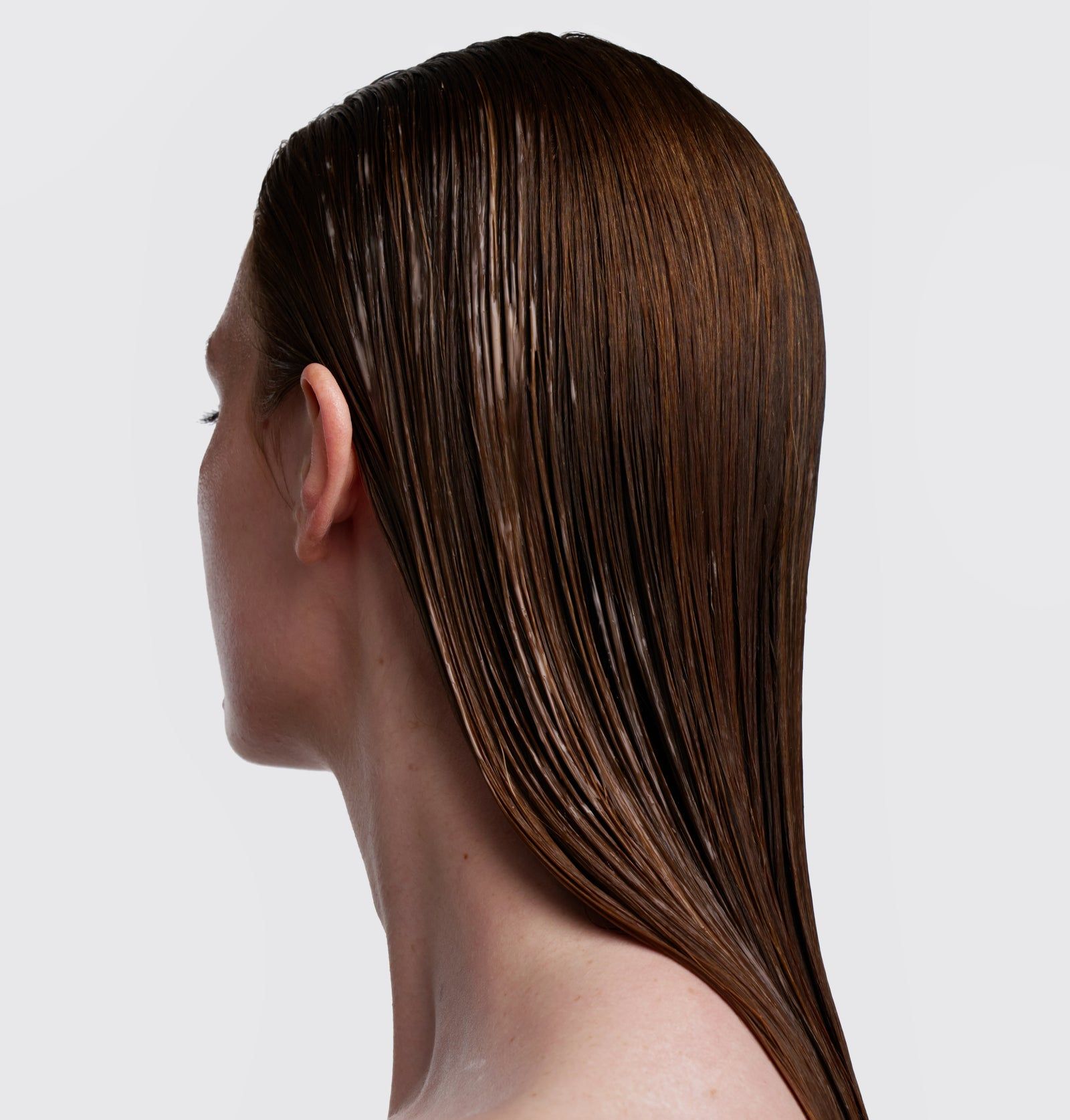 Rückansicht einer Person mit glattem, braunem Haar. Das Haar ist nass und glänzend.