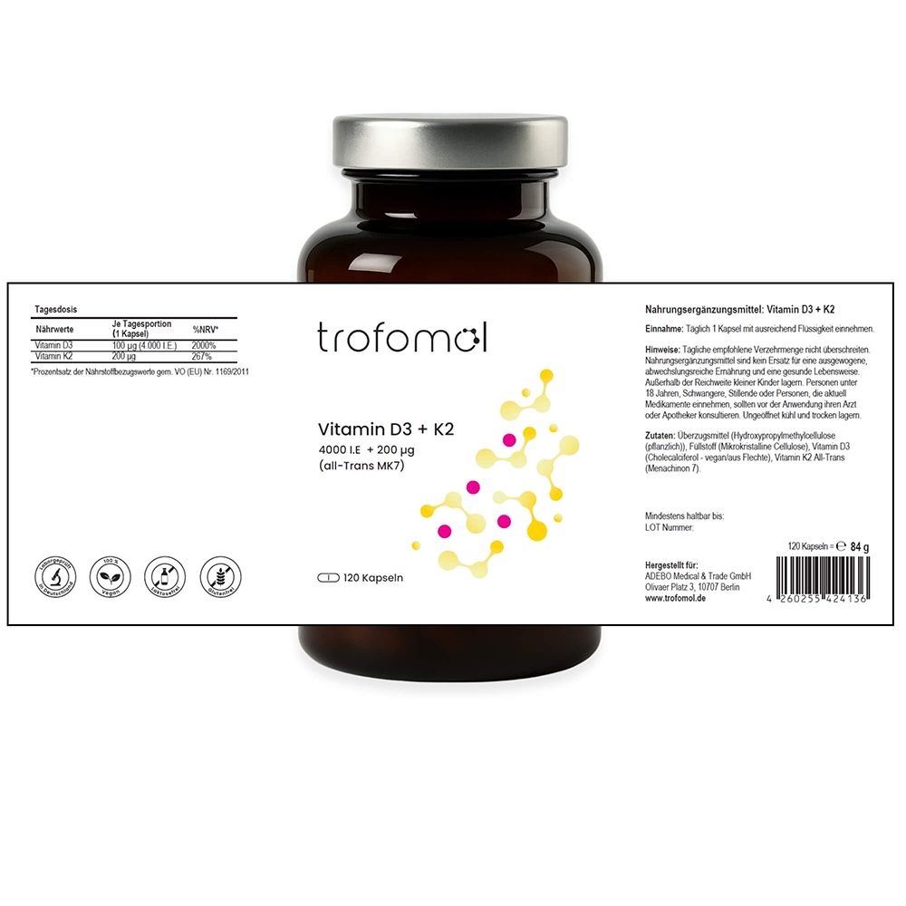 Braune Glasflasche mit weißem Etikett. TROFOMOL, Vitamin D3 + K2, 120 Kapseln. Aufgeklapptes Etikett mit Informationen. Silberner Deckel.