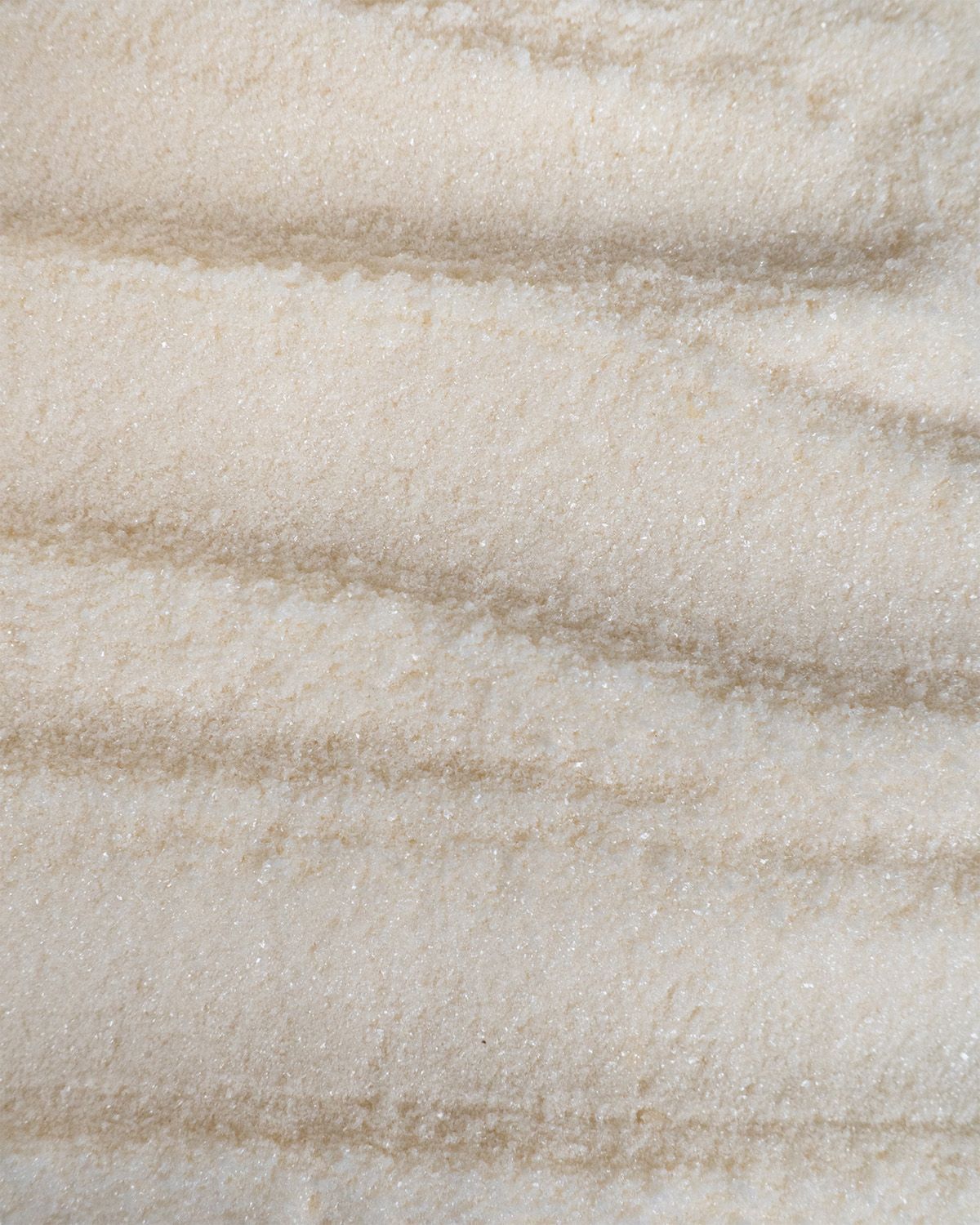 Nahaufnahme von cremefarbenem Pulver mit braunen Streifen, Textur.