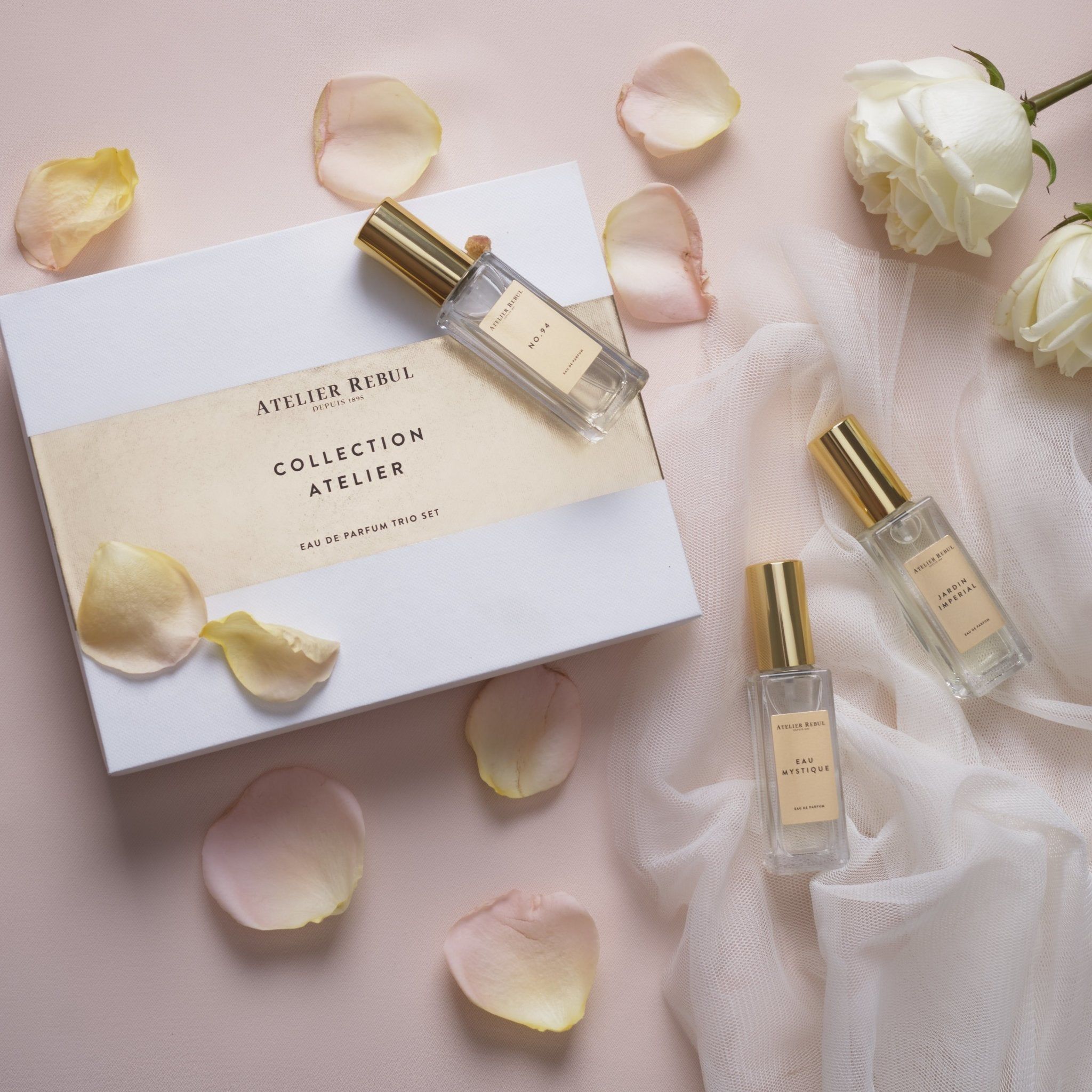 Atelier Rebul Collection Atelier Eau de Parfum Trio Set mit drei Flakons und Rosenblättern.