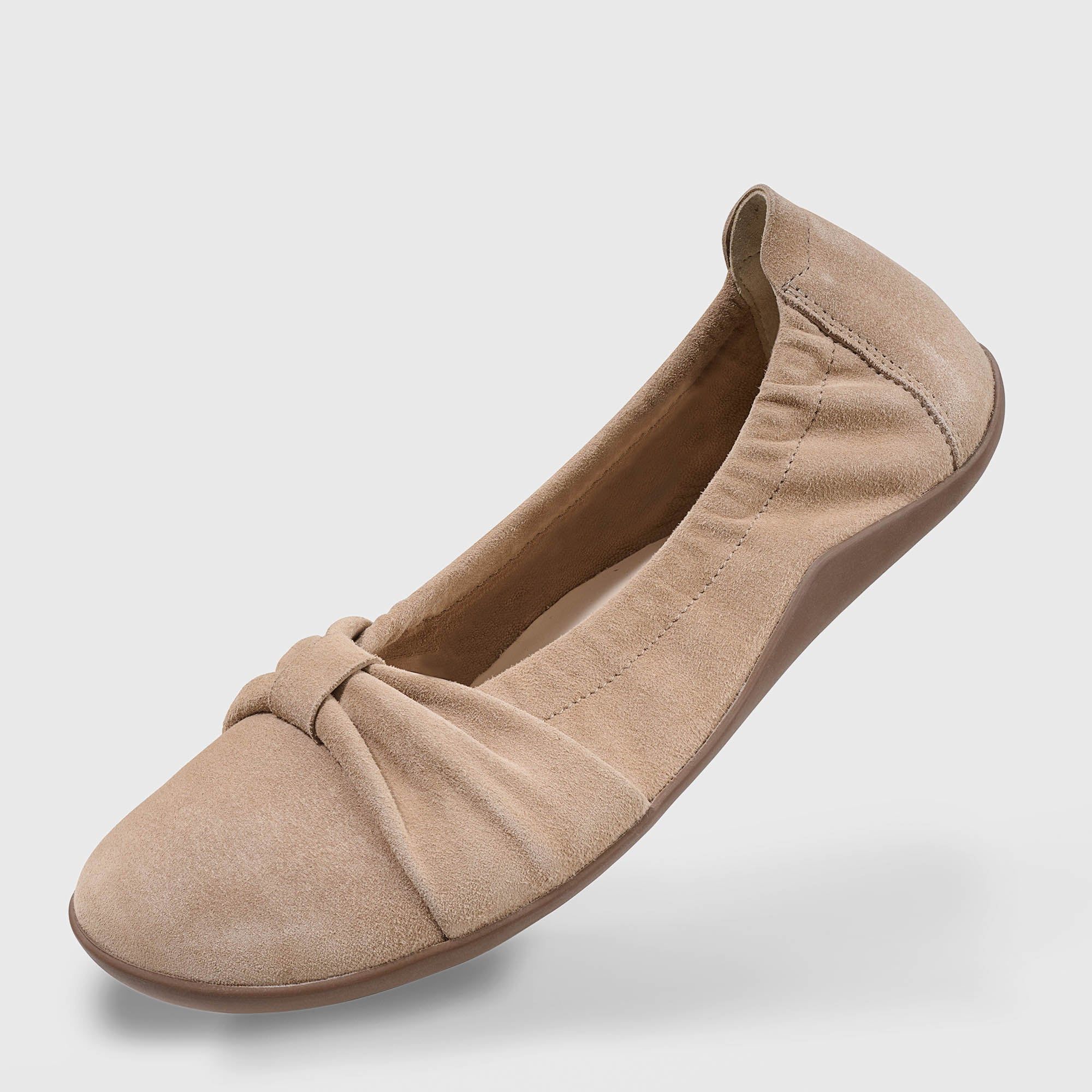 Beigefarbene Ballerina aus Wildleder. Runde Spitze, Schleife auf dem Vorderfuß. Perspektivische Ansicht.