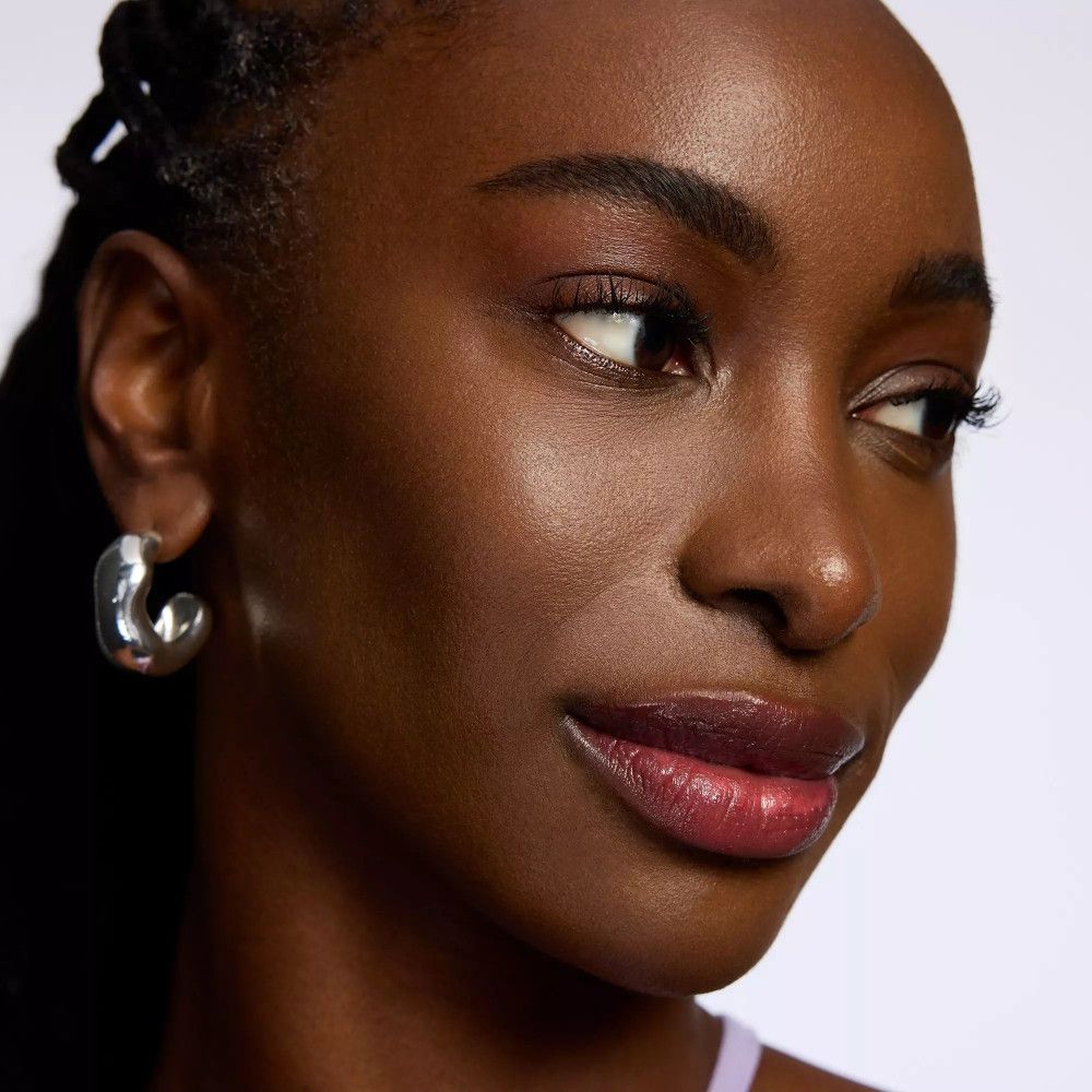 Porträt einer Frau mit dunkler Haut. Lippen mit rotem Lippenbalsam betont.