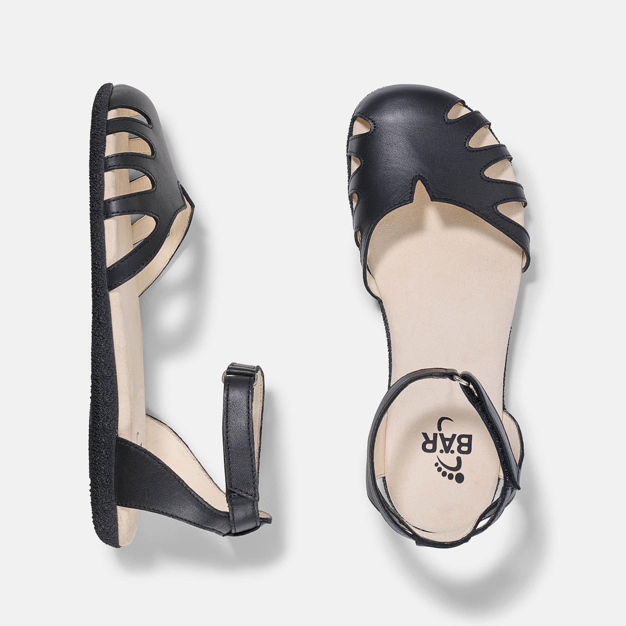 Zwei schwarze Sandalen. Eine von oben, eine von der Seite. Marke BÄR auf der Innensohle.