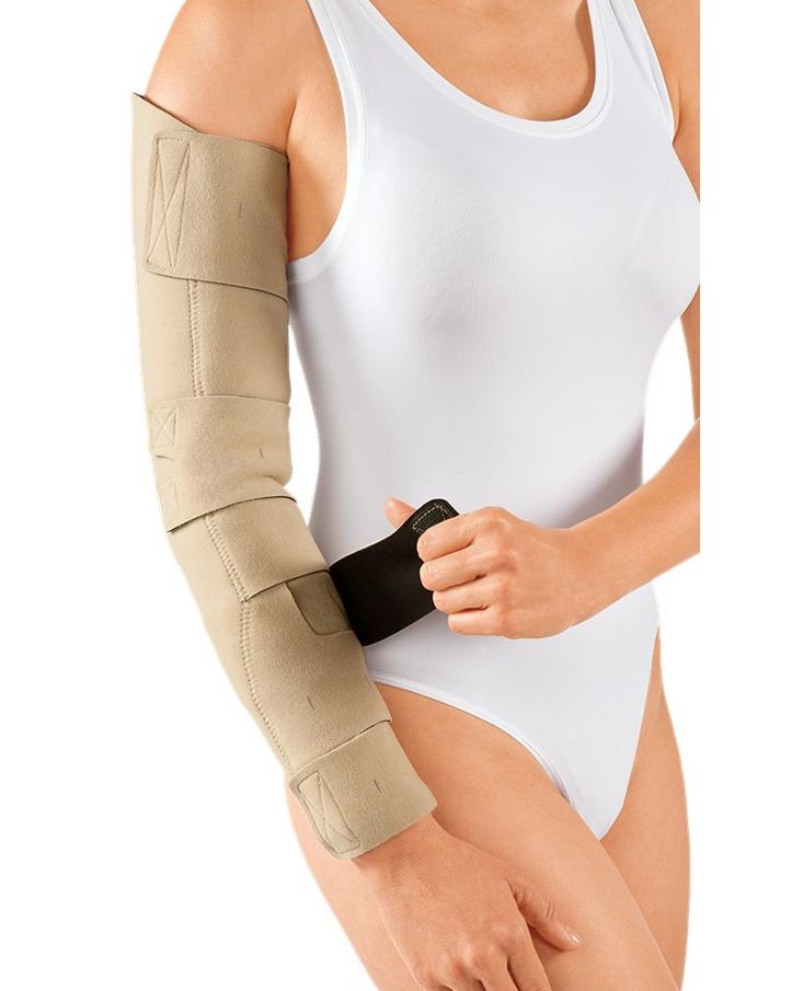 Beiges Armkompressionssystem mit Klettverschlüssen, am Arm einer Person getragen. Eine Hand hält einen schwarzen Einsatz.