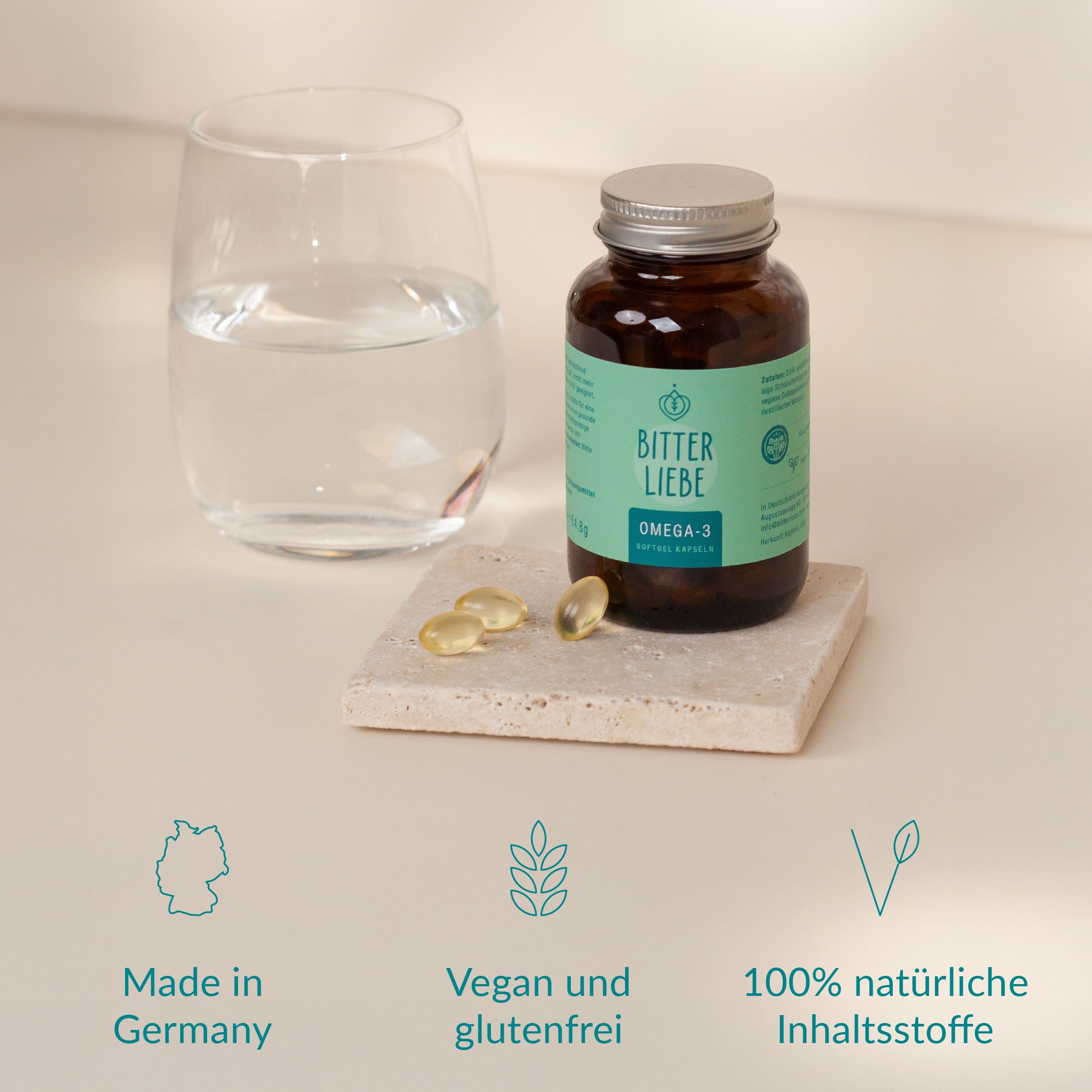 Braune Glasflasche mit Kapseln, daneben ein Glas Wasser. Aufschrift: BitterLiebe Omega-3. Vegan und glutenfrei.