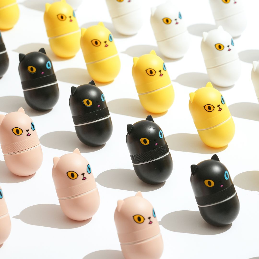 Viele Haruen Oil Monster in Katzenform, auf weißem Hintergrund. Farben: Gelb, Schwarz, Rosa, Weiß. Jedes hat eine andere Augenfarbe.