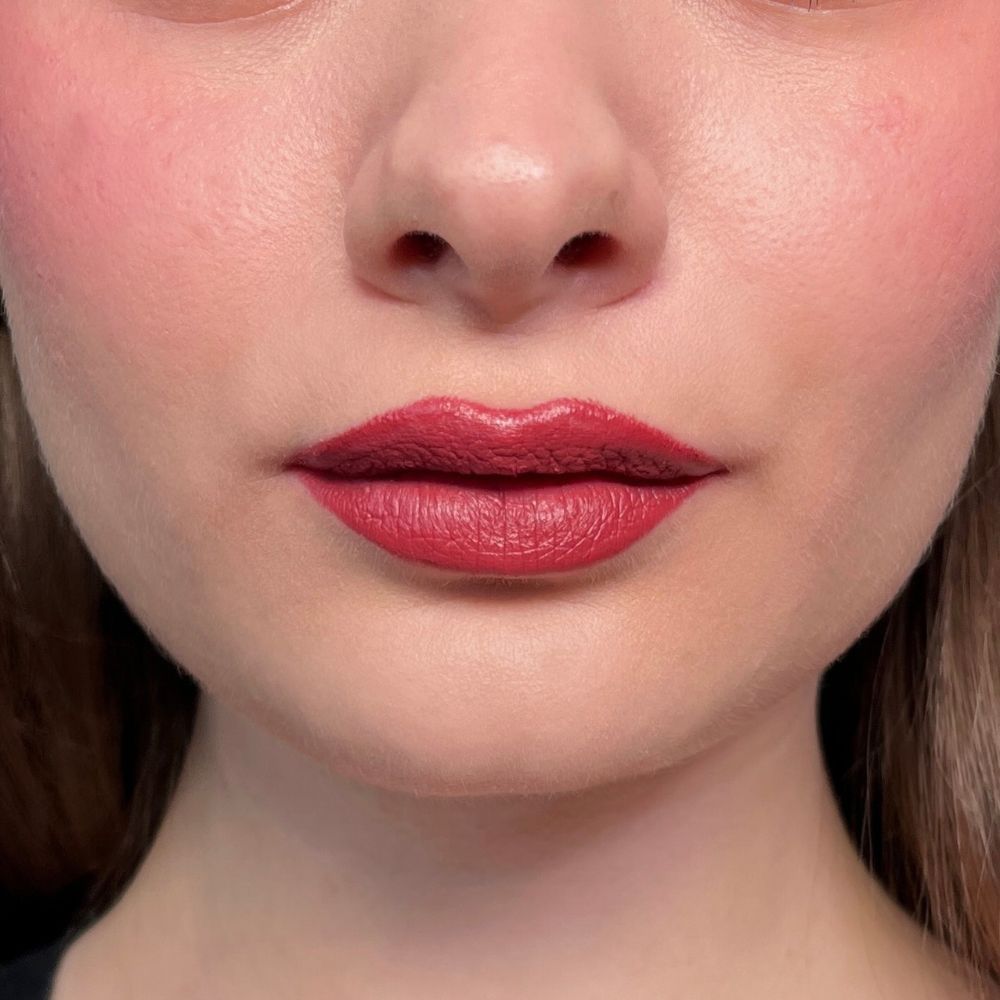 Nahaufnahme von Lippen mit rotem Lippenstift. Hautfarbener Hintergrund.