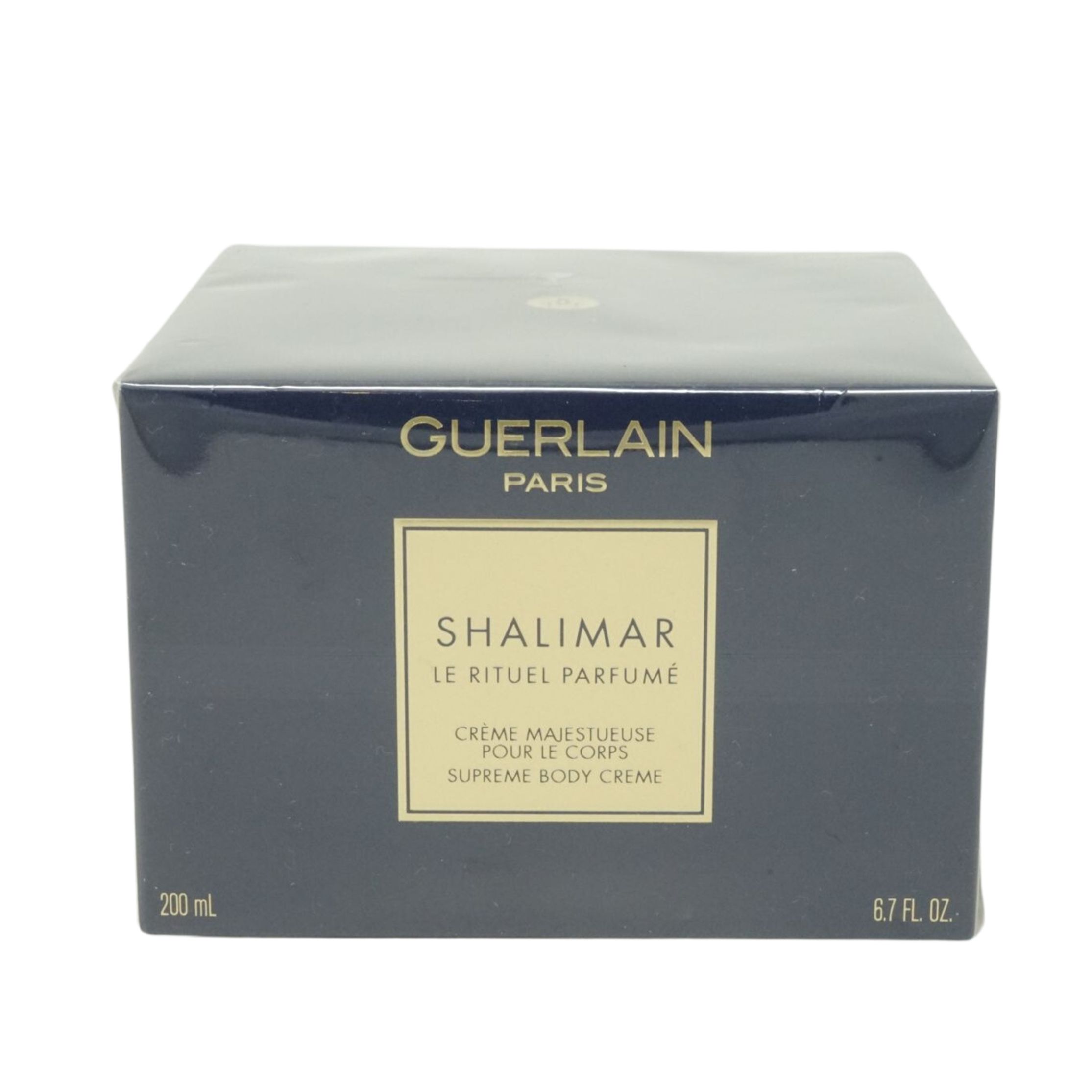 Dunkelblaue Schachtel mit goldfarbenem Etikett. Aufschrift: Guerlain Paris, Shalimar Le Rituel Parfumé, Supreme Body Cream.