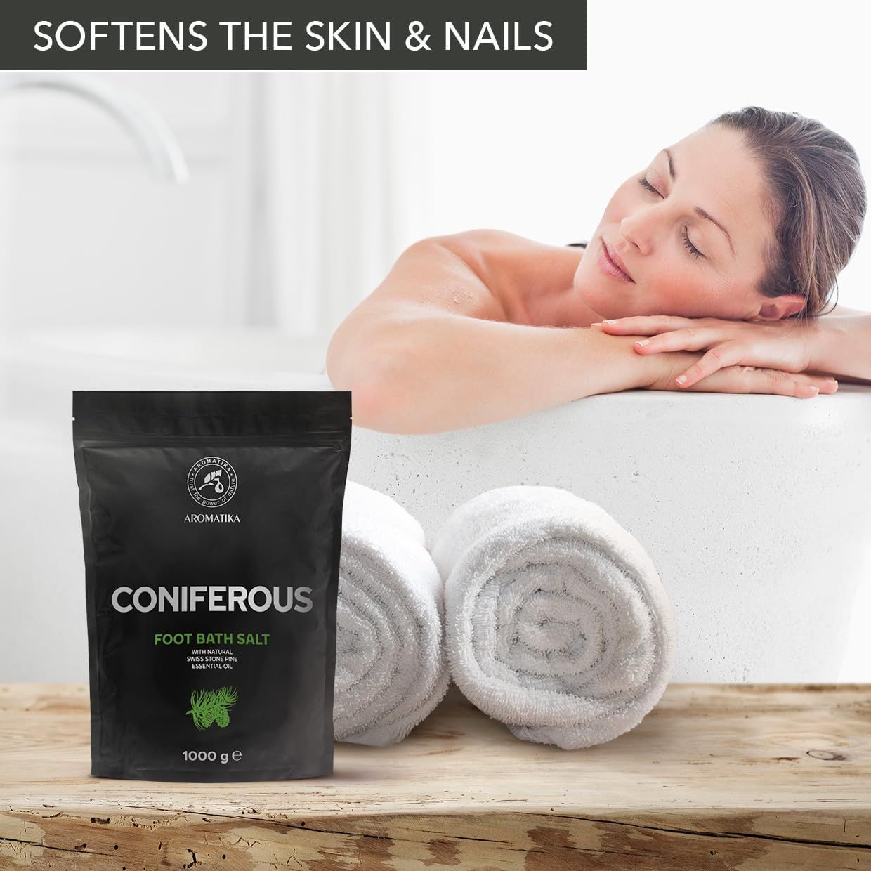 Schwarze Verpackung mit CONIFEROUS Fußbadesalz neben Frau in Badewanne. Handtücher daneben. Text: SOFTENS THE SKIN & NAILS.