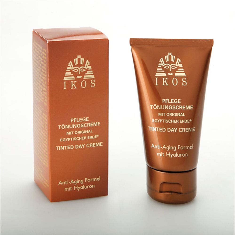 Braune Tube und Schachtel. Aufschrift: IKOS, Pflege Tönungscreme, Tinted Day Creme, Anti-Aging Formel. Ägyptische Erde.
