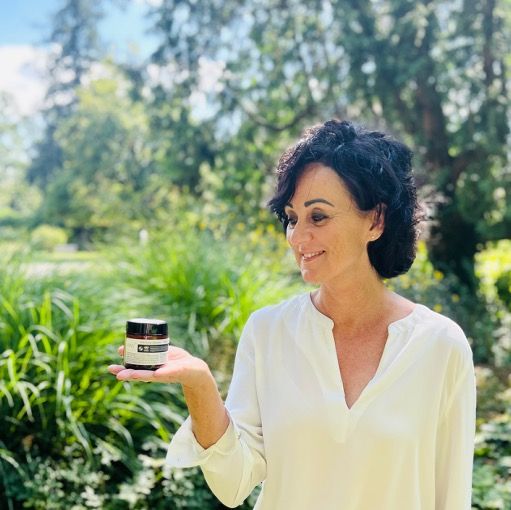 Frau hält eine braune Glasdose. Hintergrund: Natur. Logo von oxy8 Naturkosmetik.