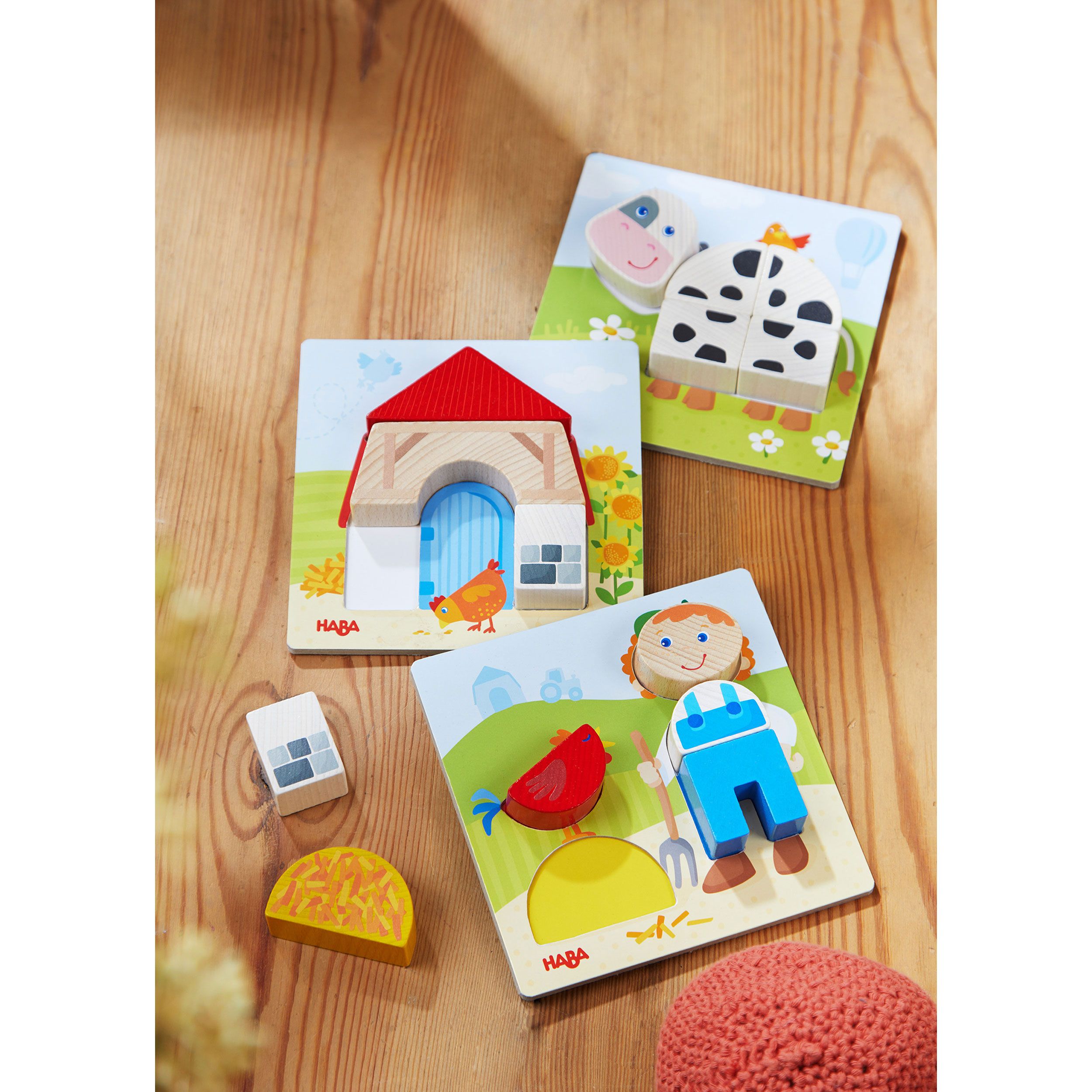 Drei Puzzles mit Bauernhofmotiven. Kuh, Haus und Bauer. HABA-Logo unten links. Holzspielzeug.