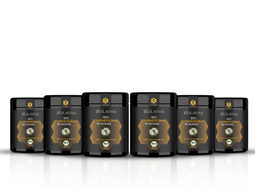 Sechs schwarze Dosen mit goldfarbenen Etiketten. Aufschrift: BIOLAVIVA BIO-Schwarzkümmel in Honig. Schwarze Deckel.