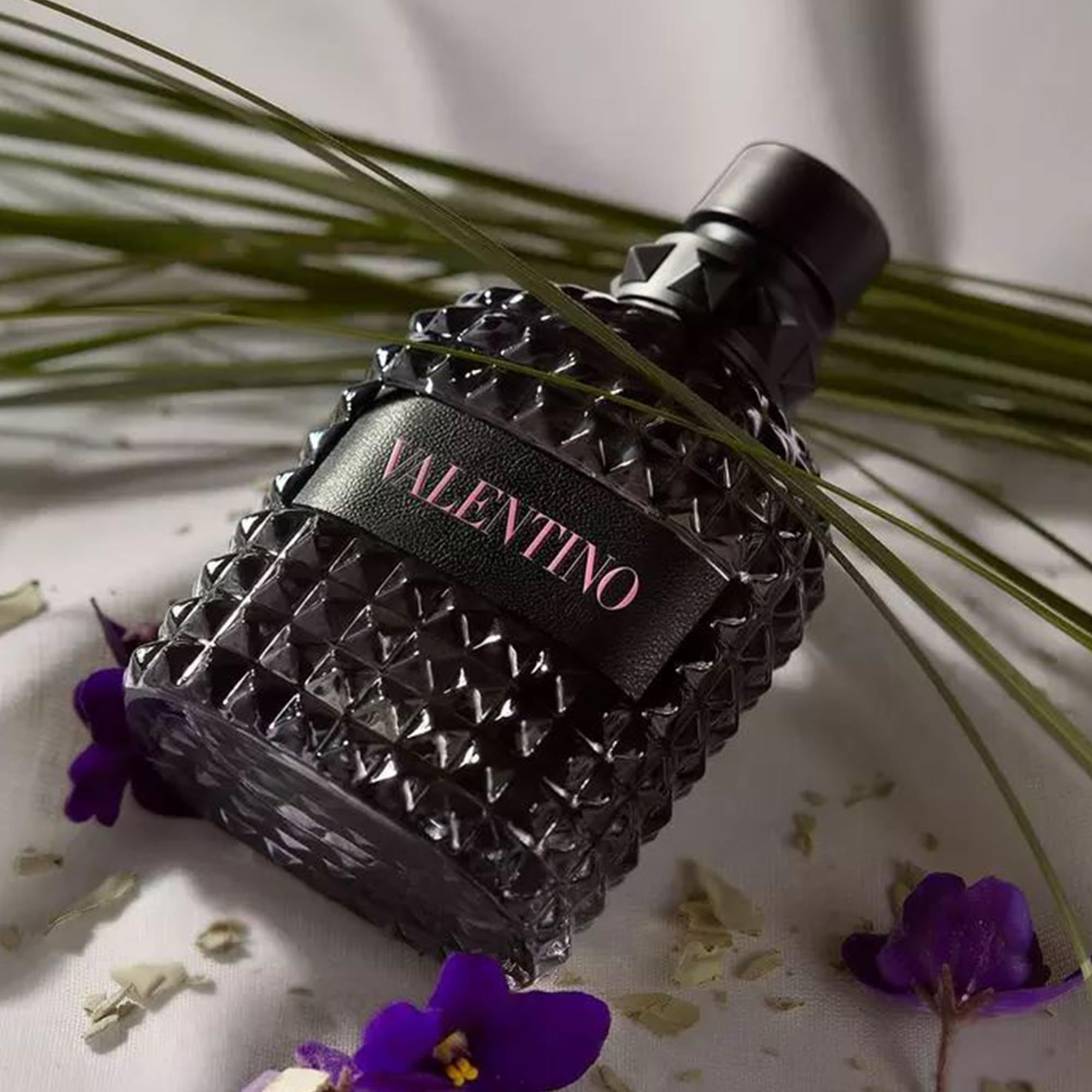 Schwarze Valentino-Parfümflasche mit Blumen. Flasche mit pyramidenförmigem Muster. Produktname: Valentino.