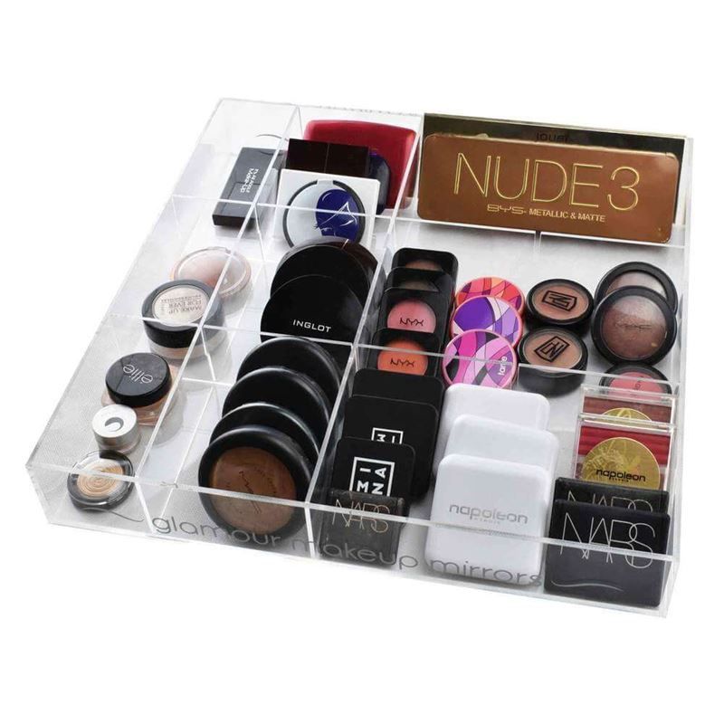 Acryl-Organizer mit 12 Fächern, gefüllt mit Make-up-Produkten. Klare, rechteckige Form. Verschiedene Kosmetikmarken sichtbar.