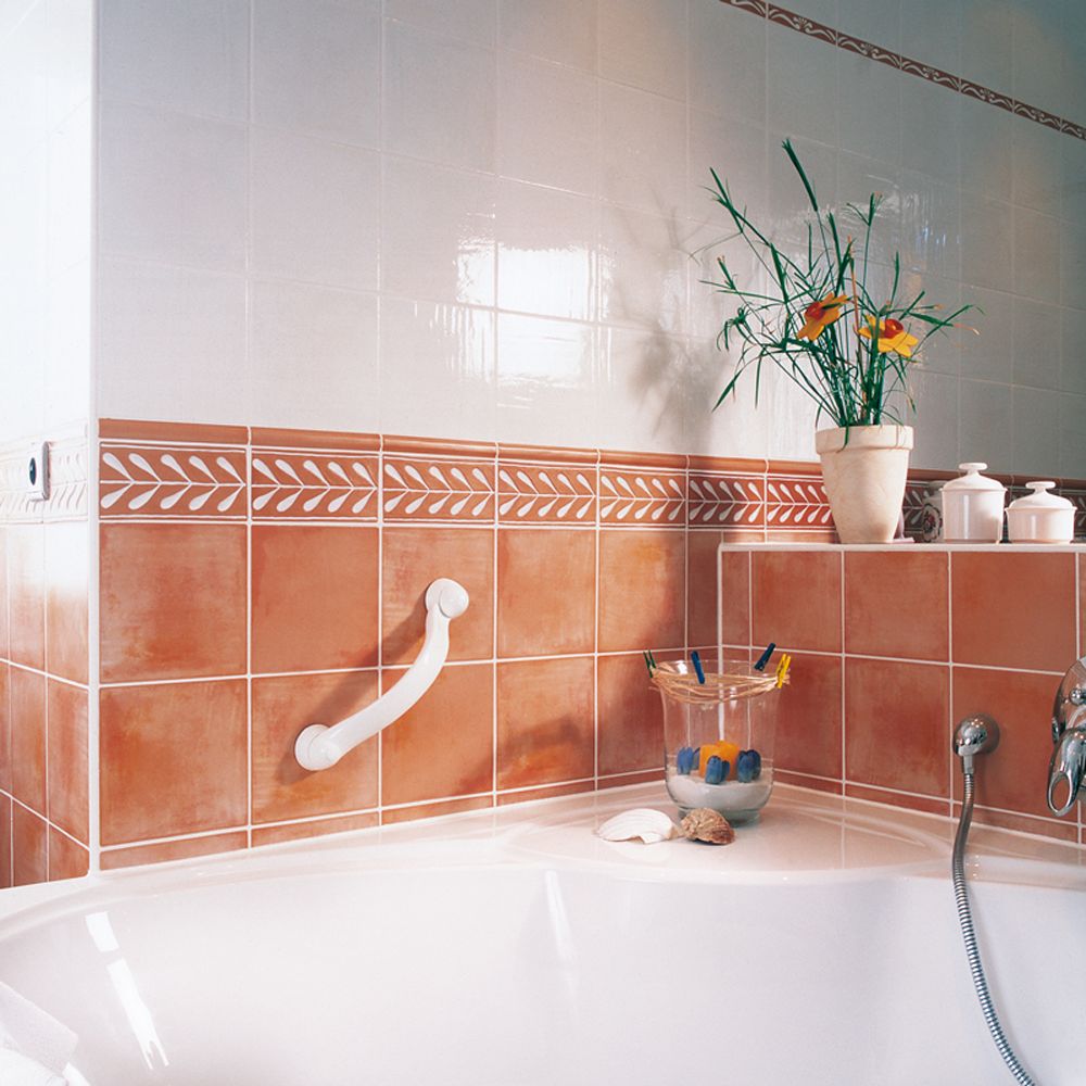 Weißer Haltegriff an einer gefliesten Wand neben einer Badewanne.