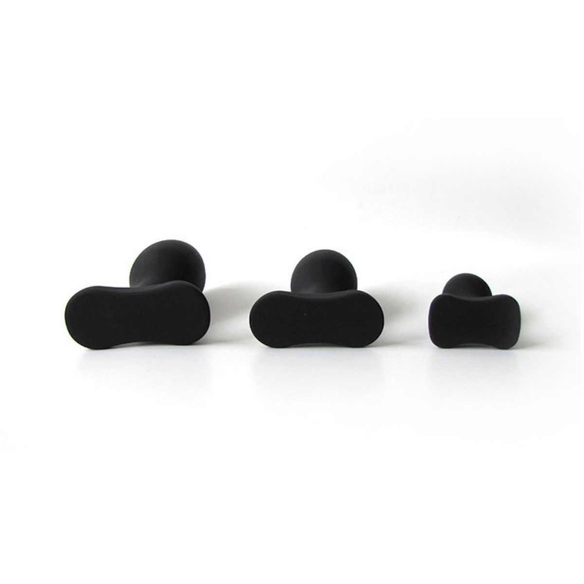 Drei schwarze Anal-Plugs. Unterschiedliche Größen, konische Form, breite Basis. Draufsicht.