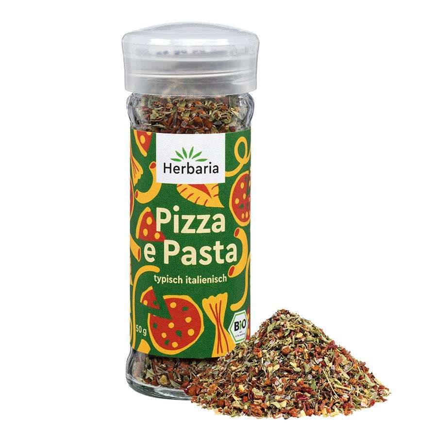 Glasflasche mit Gewürzmischung. Aufschrift: Pizza e Pasta, typisch italienisch, Bio-Siegel. Daneben ein Haufen Gewürze.