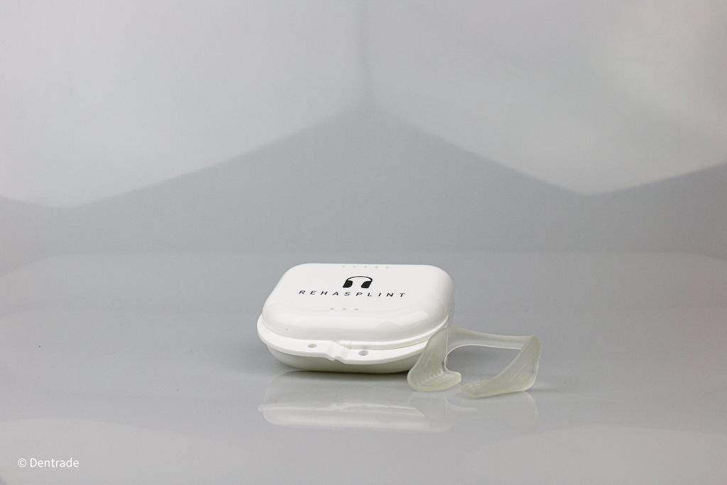Weißes Etui mit Aufdruck. Daneben eine transparente, anatomisch geformte Schiene.