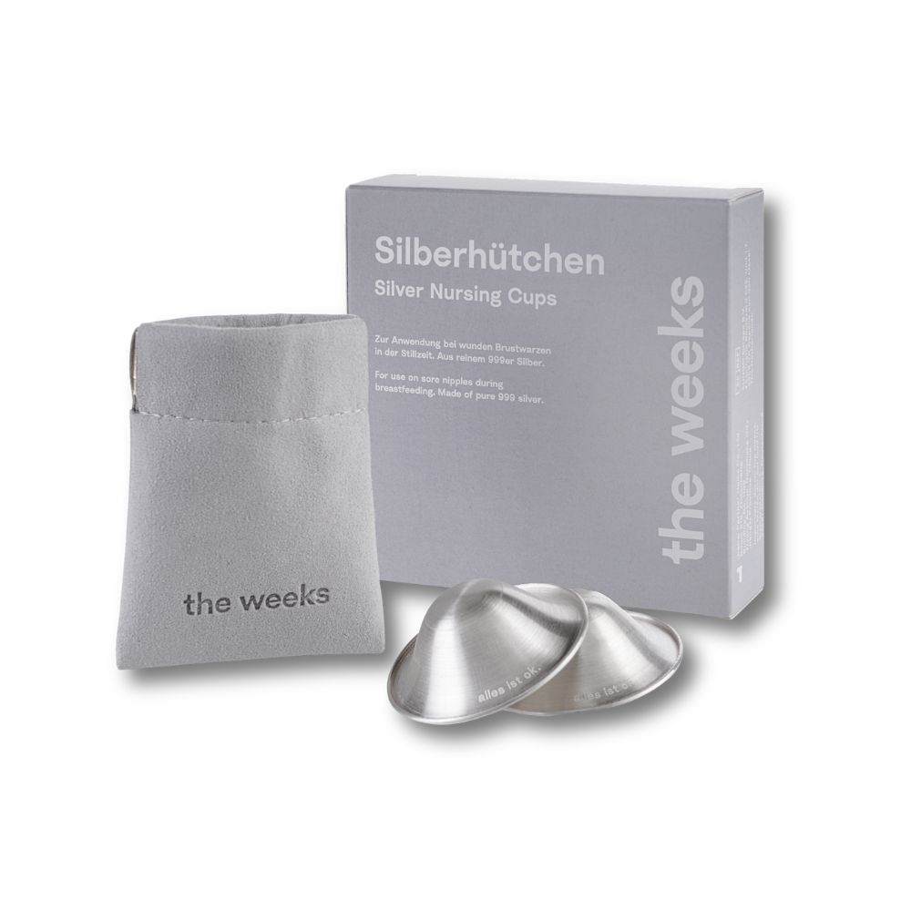 Zwei silberne Stillhütchen neben einer grauen Box und einem Beutel. Auf der Box steht "Silberhütchen" und "the weeks".