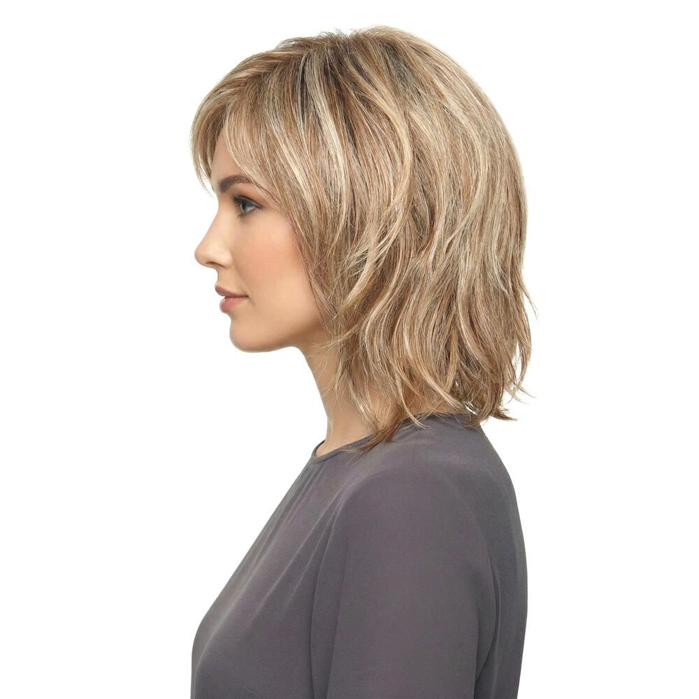 Blonde Perücke, Seitenansicht. Mittellange, gestufte Frisur. Frau mit grauem Oberteil, weißer Hintergrund.