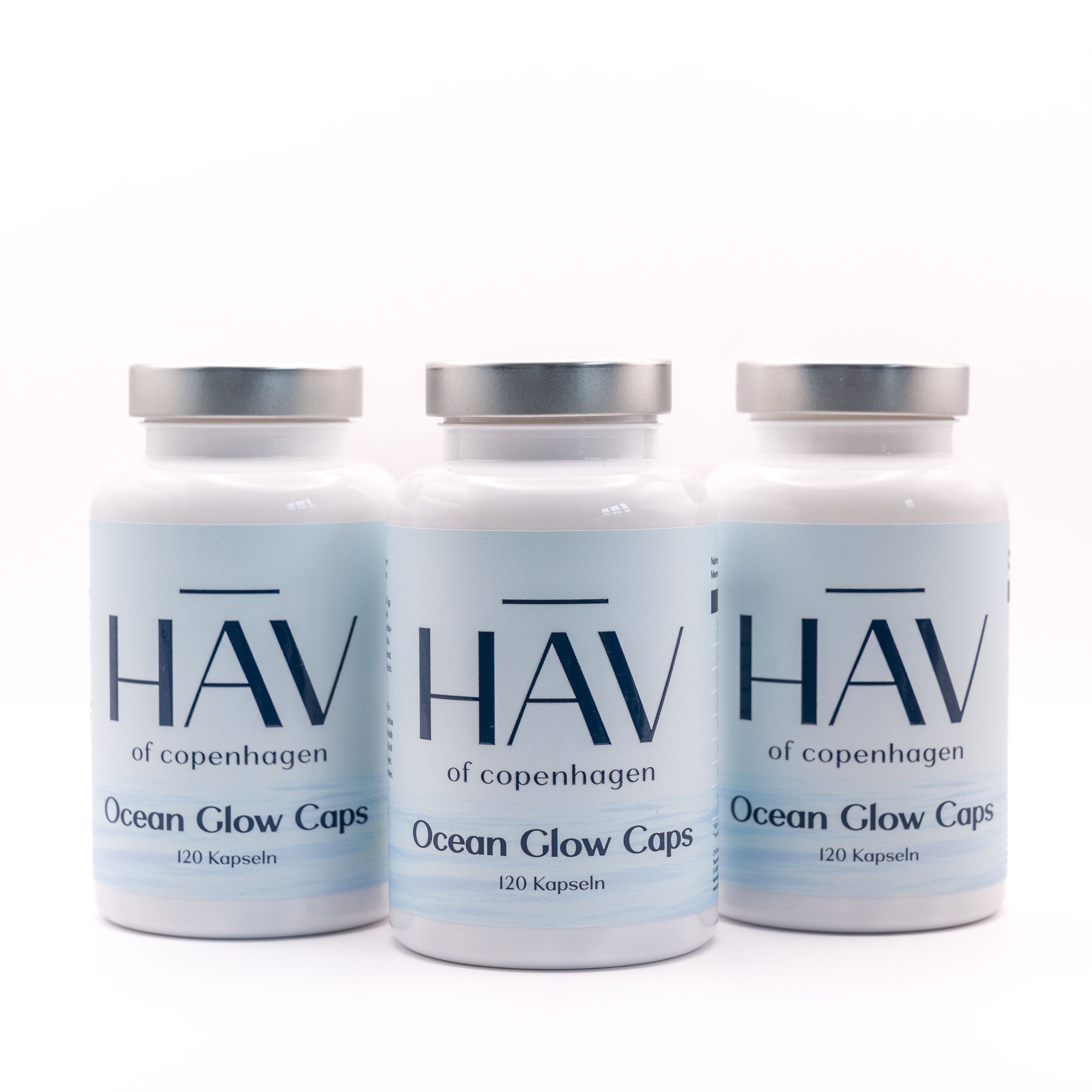 Drei weiße Flaschen HAV Ocean Glow Caps. Silberne Deckel. Blaue Etiketten mit Produktnamen und 120 Kapseln.