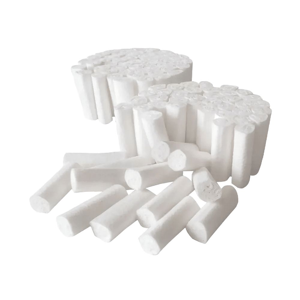 Mehrere zylindrische, weiße Wattepads, einige in Stapeln, andere lose. Die Pads sind aus weichem Material.