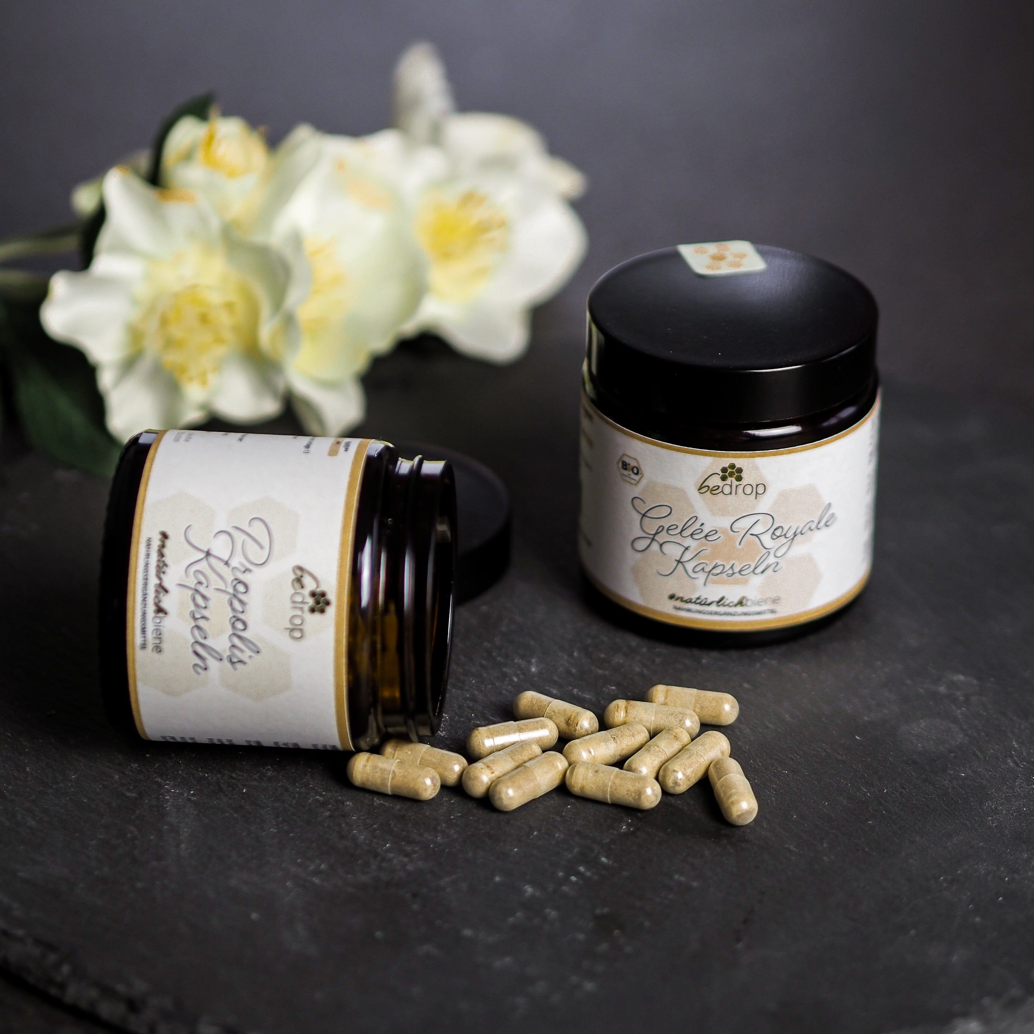 Zwei braune Gläser mit schwarzen Deckeln und Kapseln. Auf den Etiketten steht "bedrop Propolis Kapseln" und "Gelée Royale Kapseln".