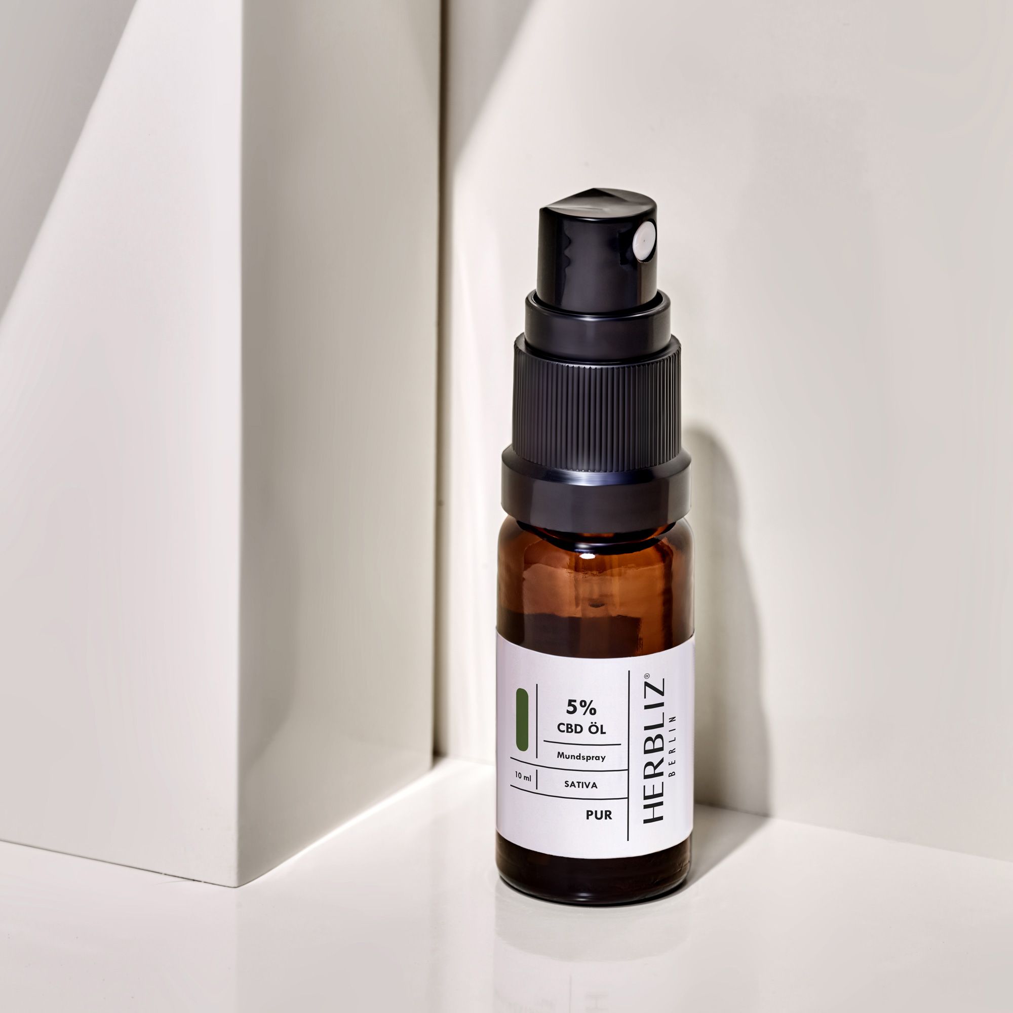 Braune Glasflasche mit Sprühkopf. Aufschrift: HERBLIZ, 5% CBD Öl, Sativa, 10 ml. Grün-weißes Etikett.