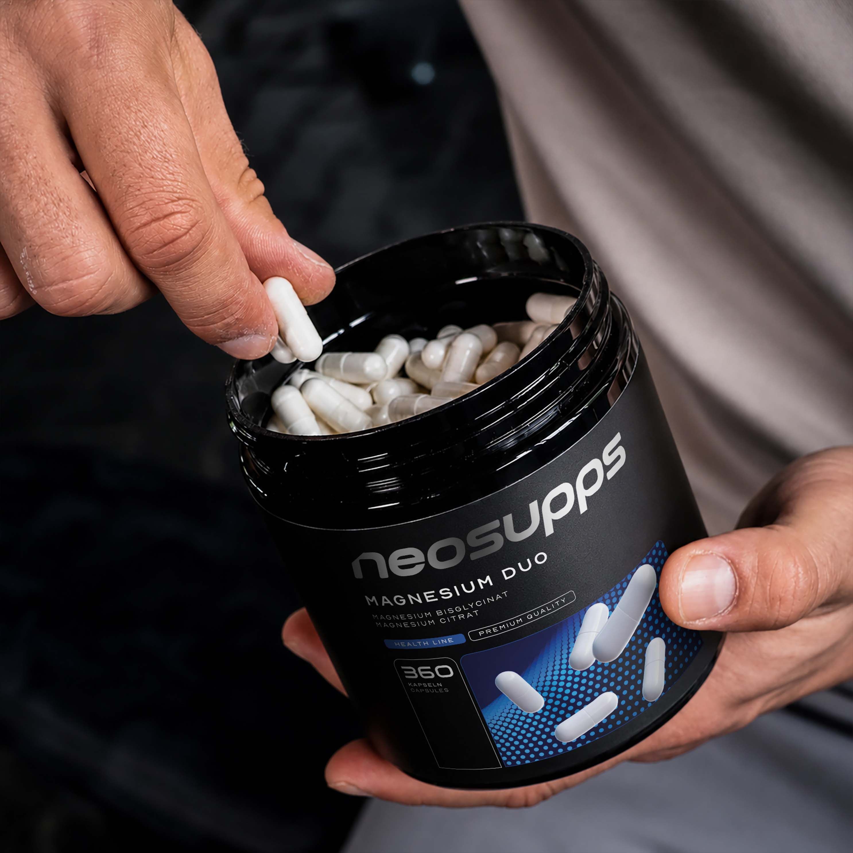 Hand entnimmt Kapsel aus Neosupps Magnesium Duo Dose mit 360 Kapseln.