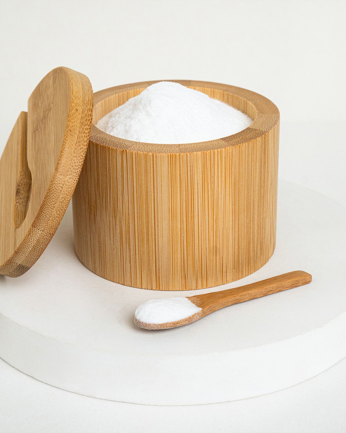 Bambusdose mit Deckel und Löffel, gefüllt mit weißem Traubenzuckerpulver.
